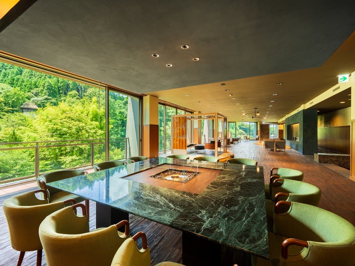 Yusai lounge with marble irori table, designer chairs and panoramic mountain-forest view
