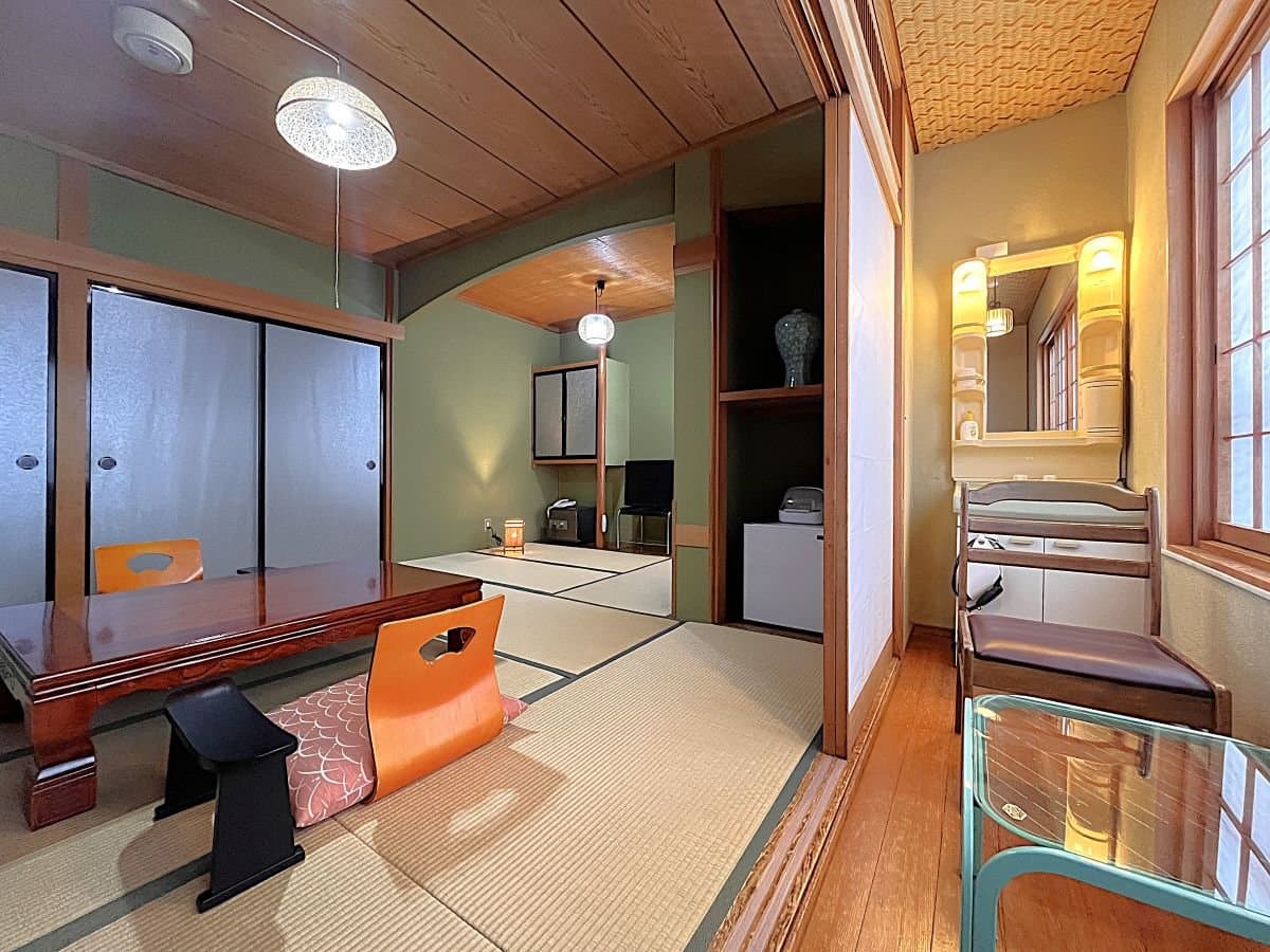 Cozy tatami guest room with green walls, a low table, vanity mirror and inner alcove