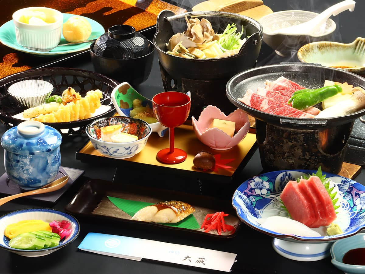 Kaiseki dinner set with sizzling wagyu beef on a hot plate, tuna sashimi and assorted small dishes