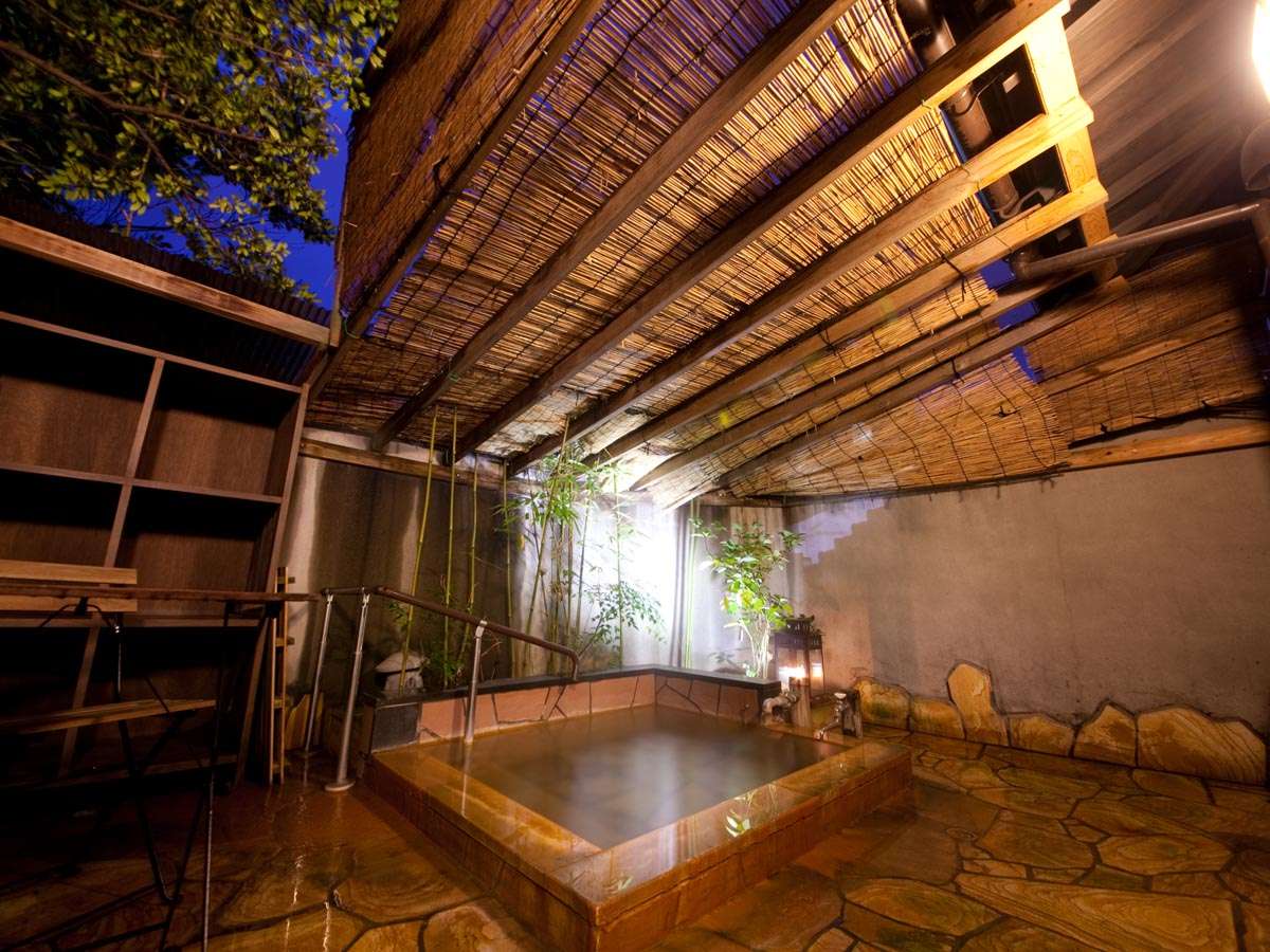 Covered private rotenburo bath under a bamboo-slat roof with stone flooring lit by lantern, Ryokan Sennari, Beppu Onsen