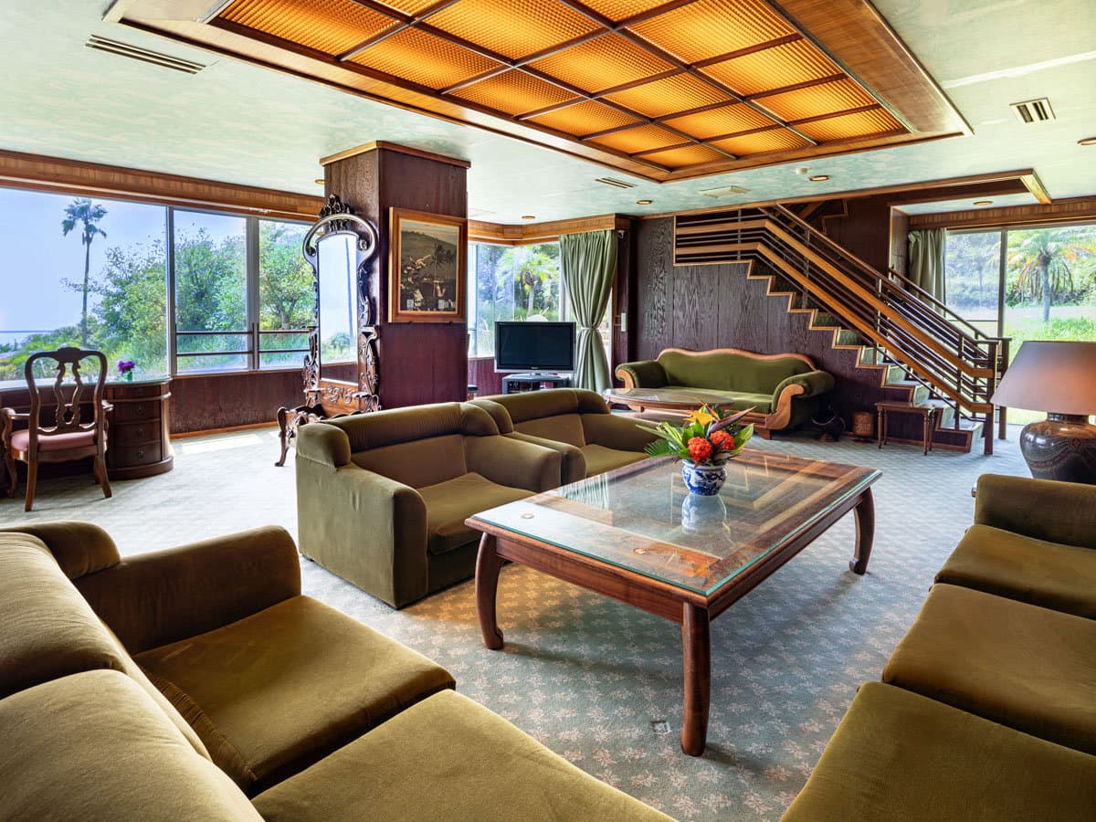 Open lounge area at Ibusuki Phoenix Hotel with green sofas, coffered ceiling and garden-facing windows
