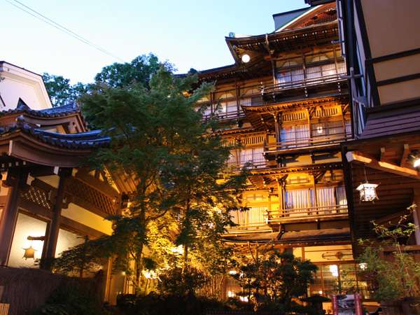 Four-story wooden facade of Kanaguya ryokan rising above Shibu Onsen at dusk