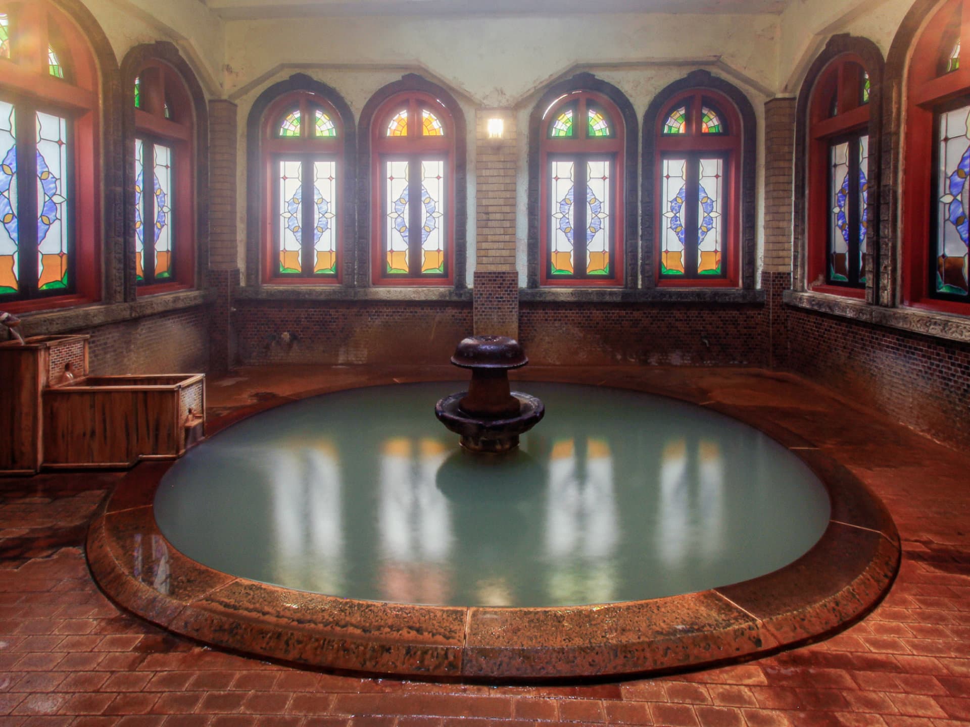 Roman-buro indoor bath: an oval stone pool beneath arched stained-glass windows