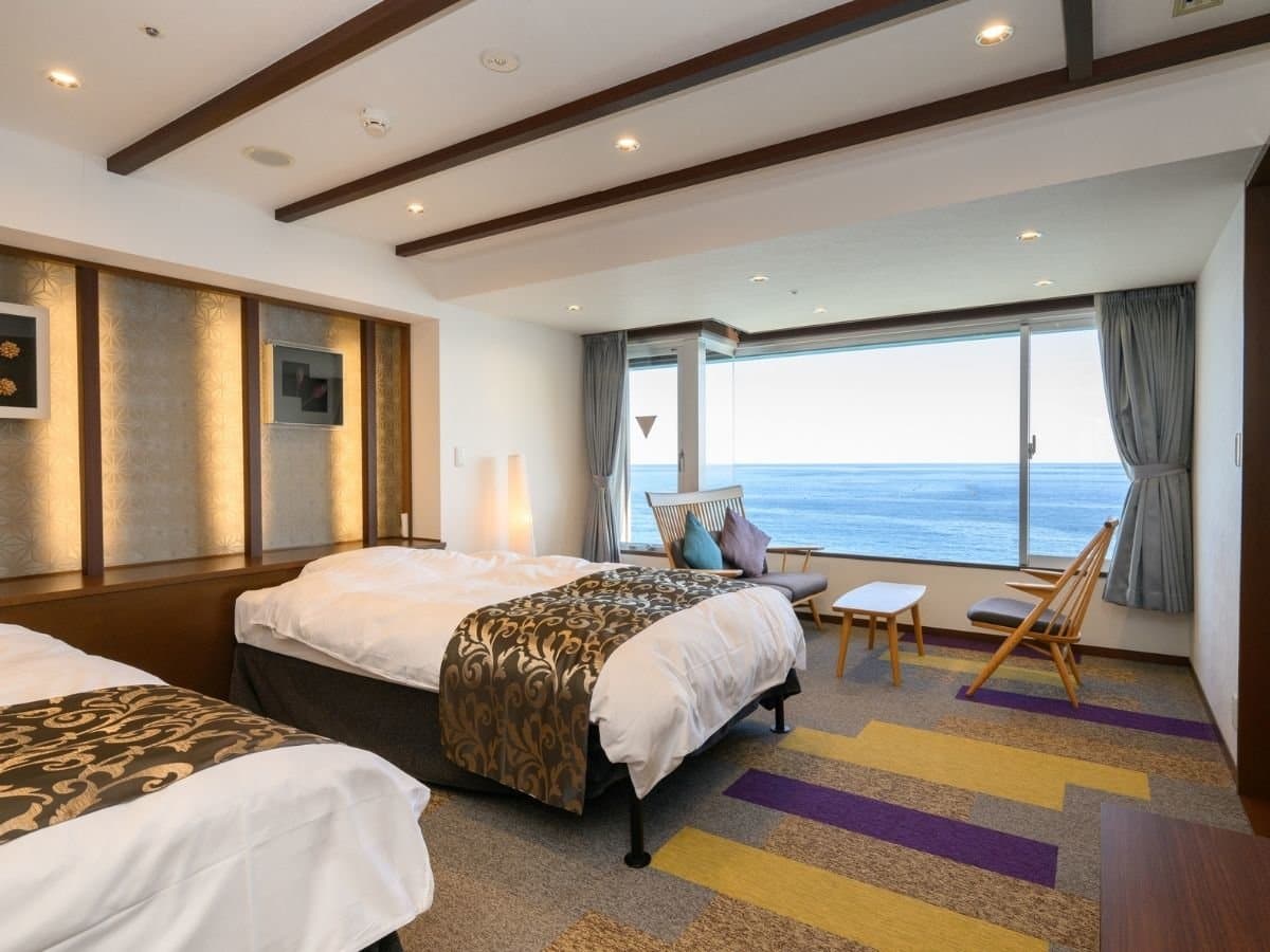 Western-style twin bedroom with sea-view window at Hotel New Sagamiya in Atami