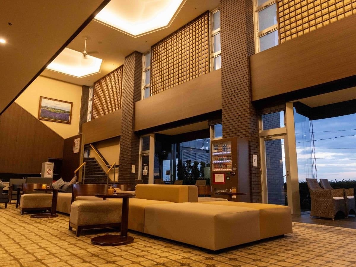 Spacious high-ceiling lobby lounge with warm wood interior at Hotel New Sagamiya