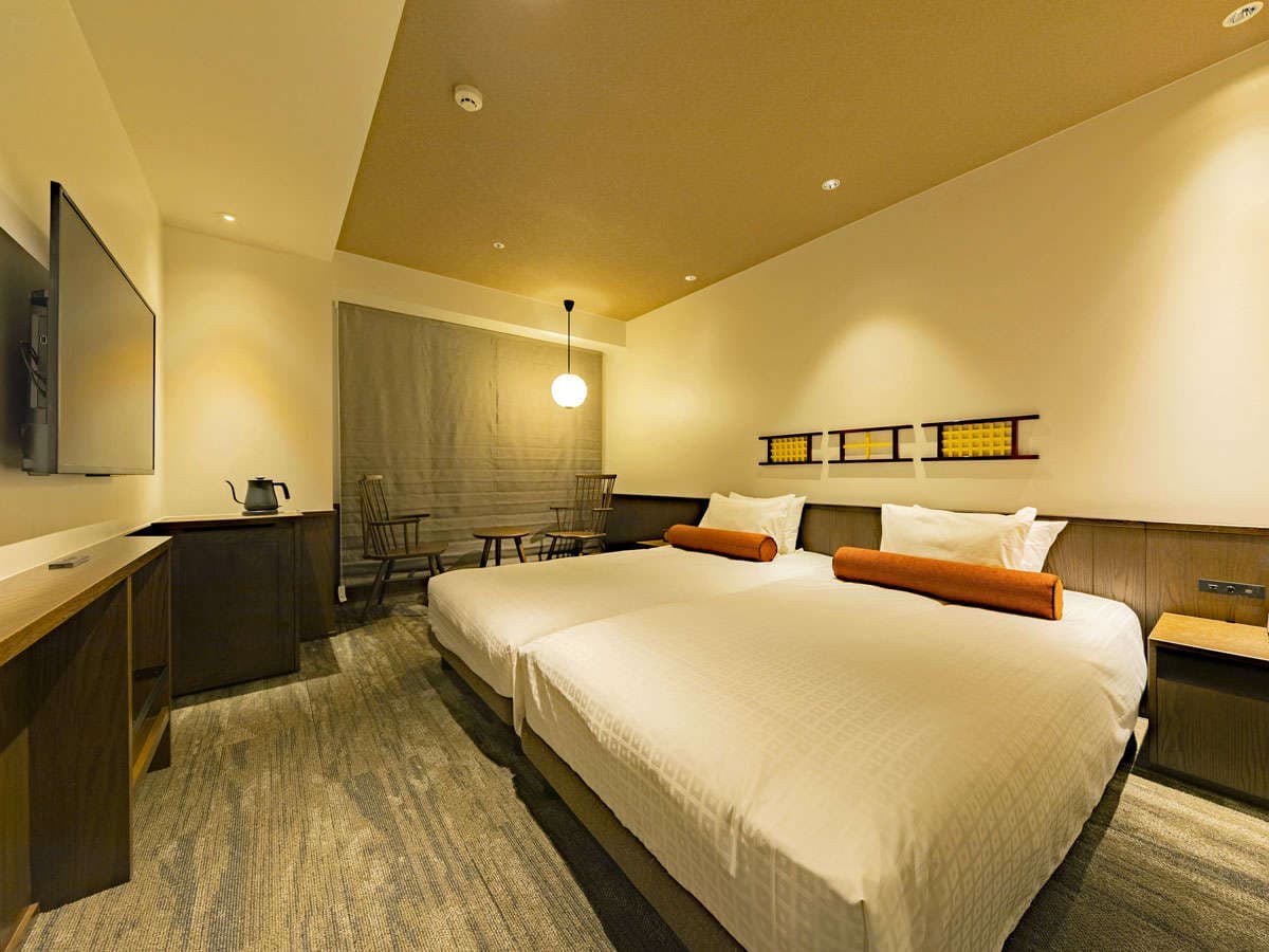 Warmly lit twin guest room with wood paneling, lattice headboard accents and bolster cushions