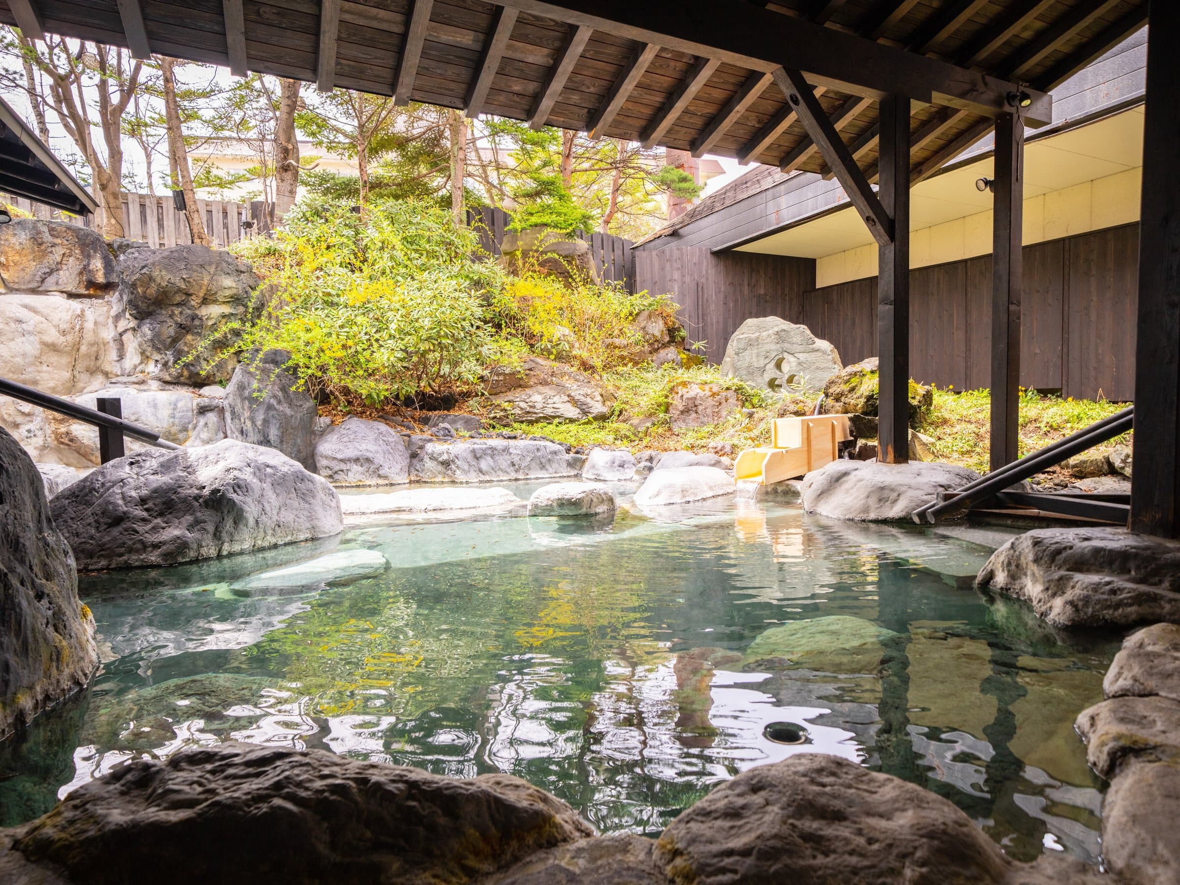 Kusatsu Now Resort Hotel outdoor rotenburo bath set among boulders and woodland greenery