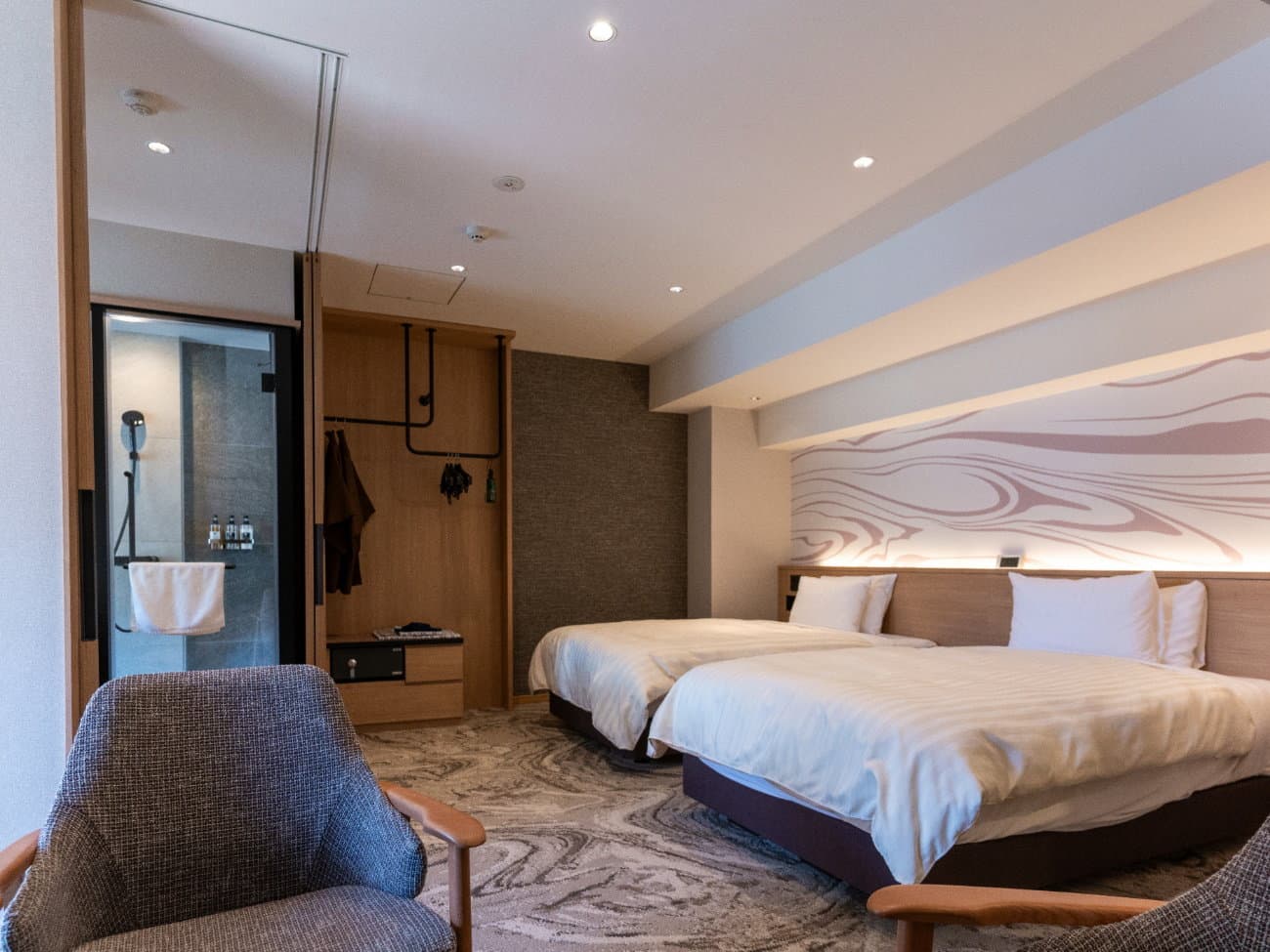 Kusatsu Now Resort Hotel modern twin guest room with marbled carpet, wood headboard wall and glass-walled bathroom
