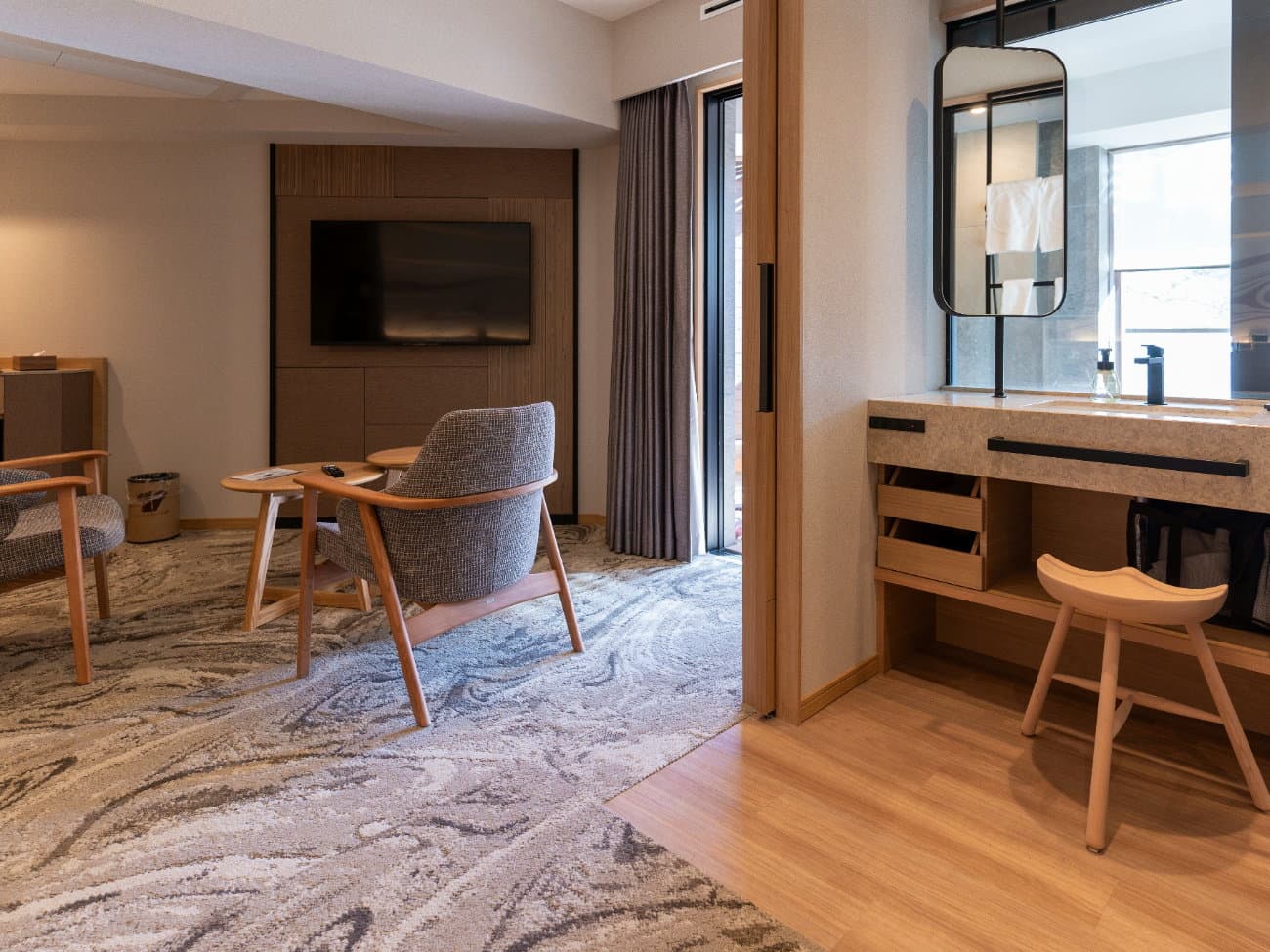 Kusatsu Now Resort Hotel guest room lounge corner with armchairs, low table, TV and a stone vanity counter