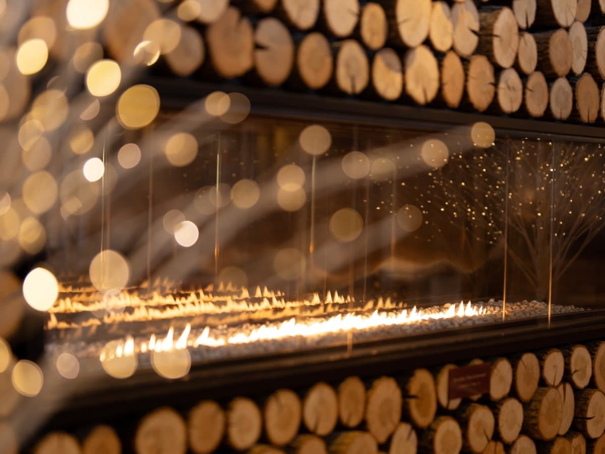 Kusatsu Now Resort Hotel atmospheric detail, a long gas fireplace set into a stacked-log feature wall with warm bokeh