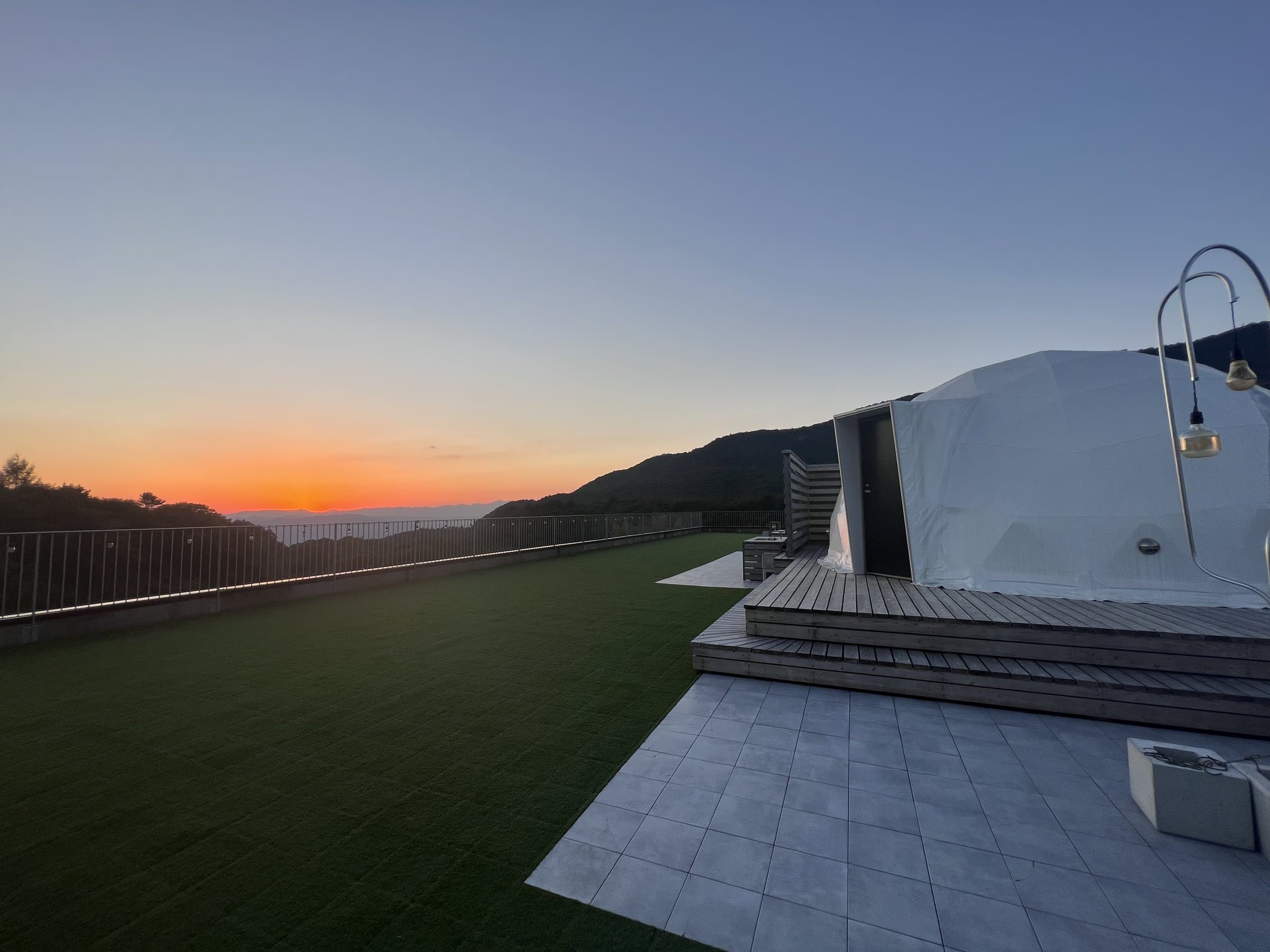 Rooftop glamping dome on a grass terrace overlooking the Zao mountains at sunset