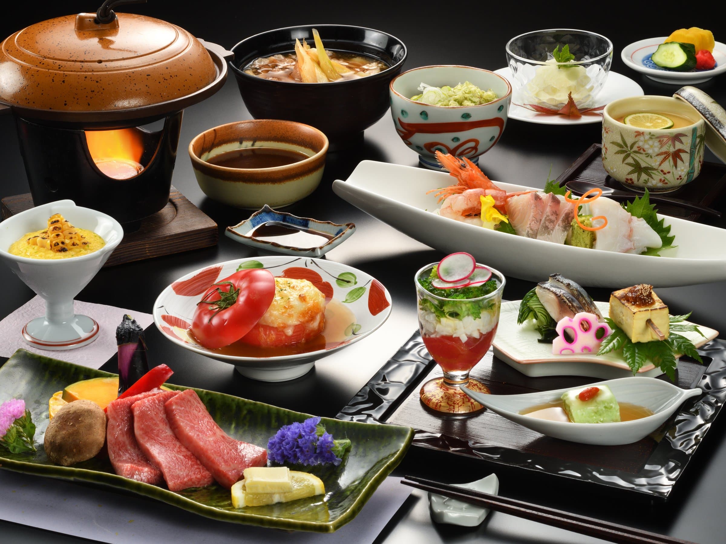 Multi-course kaiseki dinner with Yamagata beef, sashimi and small dishes served on a dark table