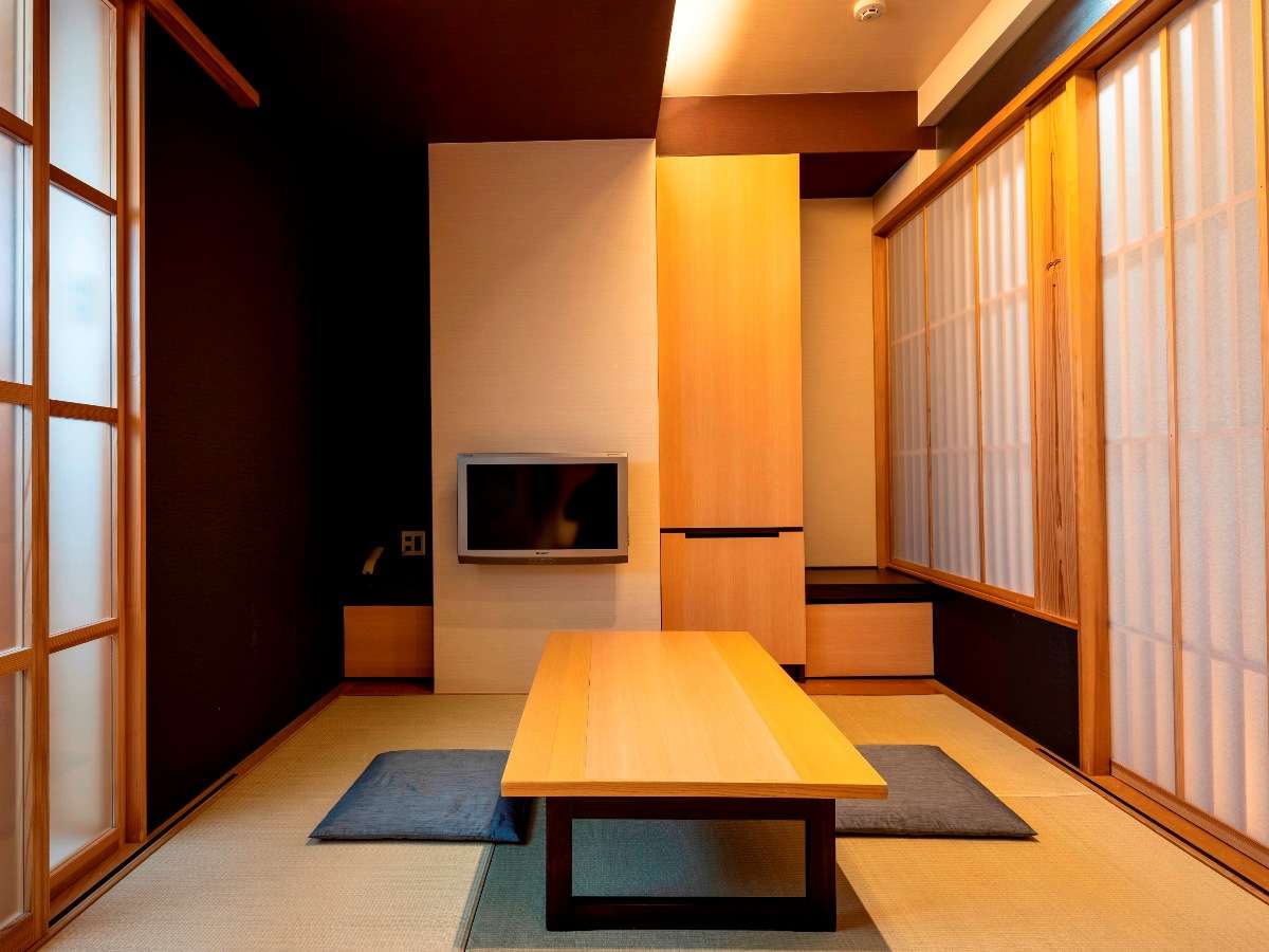 Japanese-style tatami guest room with low wooden table, floor cushions and shoji-screen windows