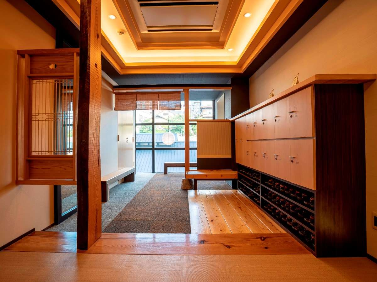Entrance genkan area with wooden shoe lockers, raised plank flooring and a terrace beyond