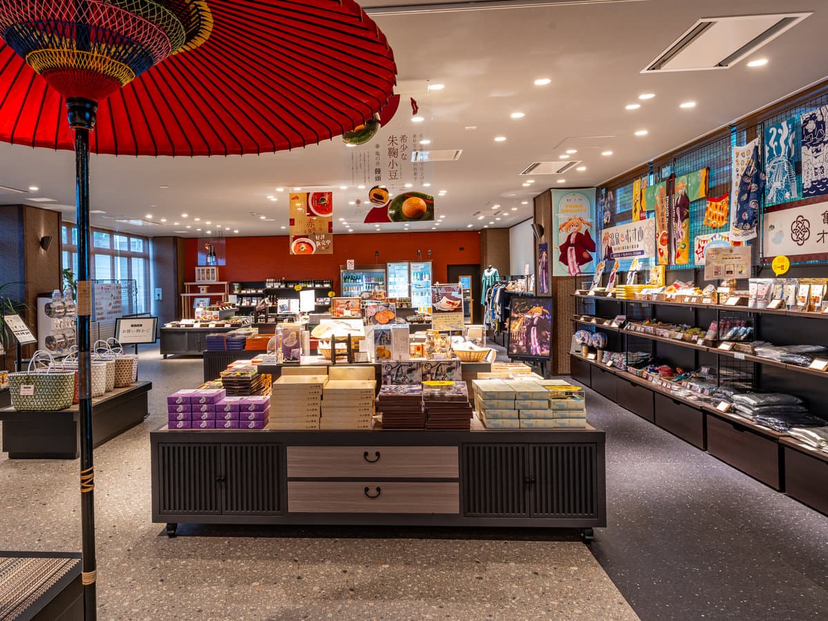 Hotel souvenir shop interior with a red Japanese paper umbrella and shelves of Gunma specialty goods