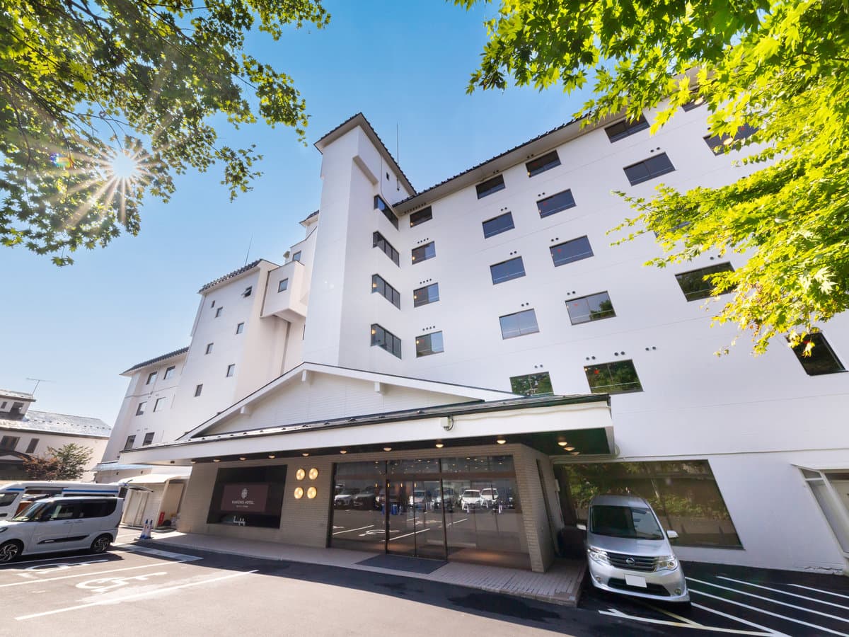 Kamenoi Hotel Kusatsu Yubatake white multi-storey building exterior under clear blue sky