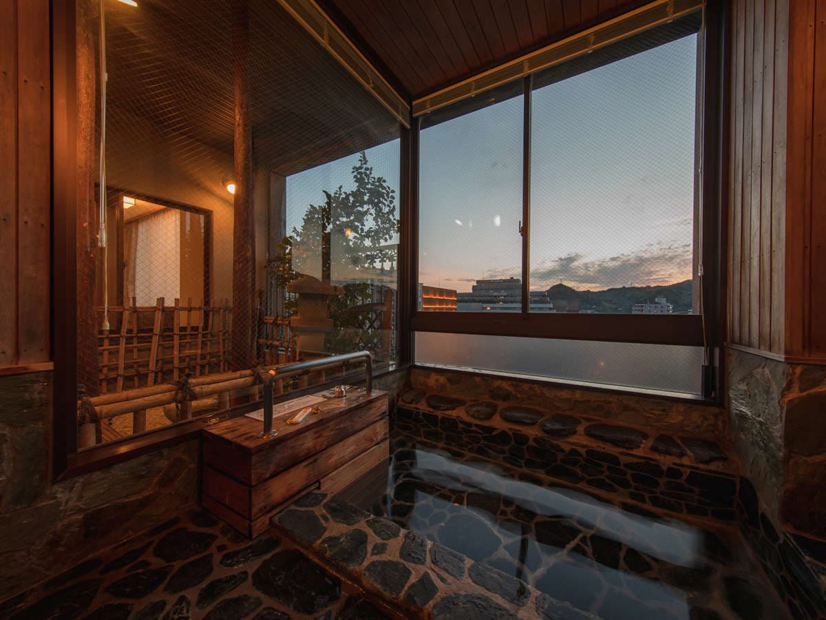 Private in-room stone bath at Hotel Tsubakikan overlooking the Dogo townscape at sunset