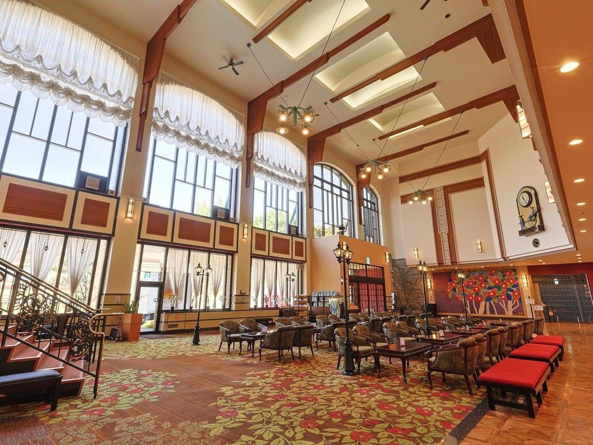 Grand high-ceilinged lobby lounge at Hotel Tsubakikan with arched windows and floral carpet, Dogo Onsen