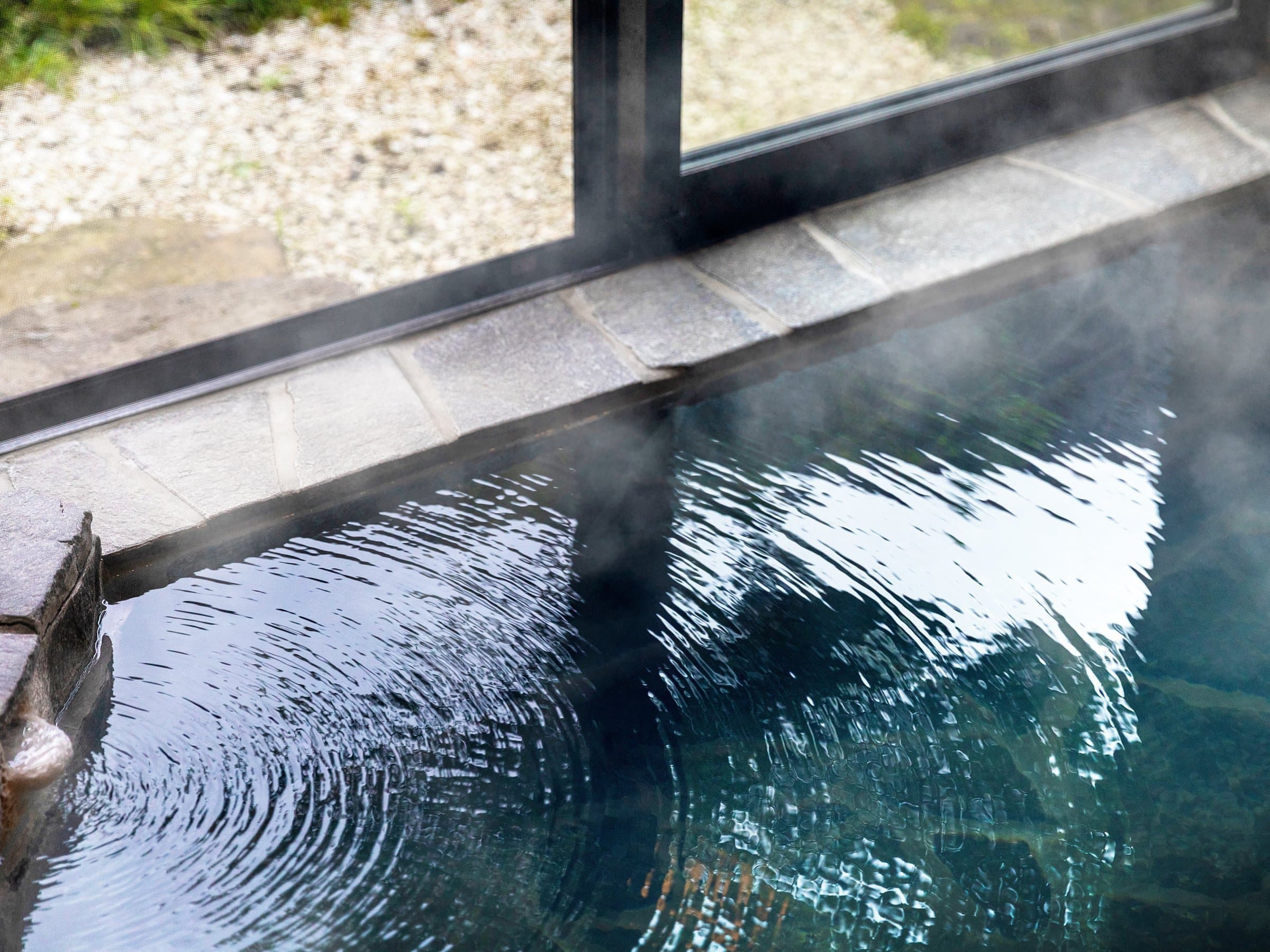 Steam rising from the still surface of a hot-spring bath at Yufuin Yufusaryo