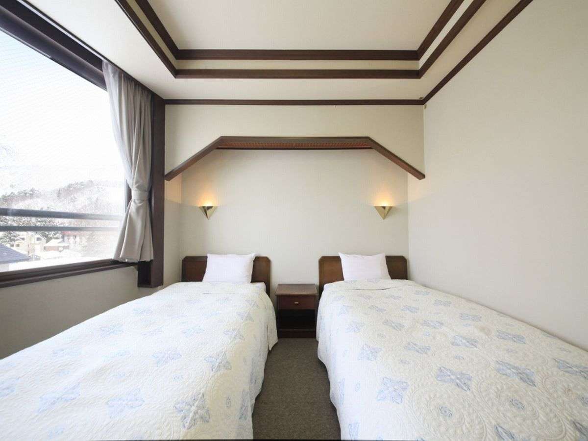 Western-style twin bedroom with wood trim ceiling at Zao Plaza Hotel
