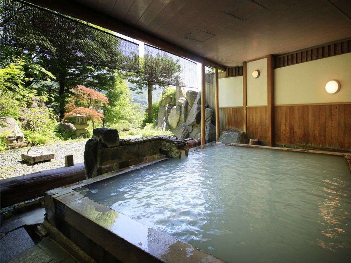 Open-air hot spring bath overlooking a landscaped Japanese garden at Zao Plaza Hotel