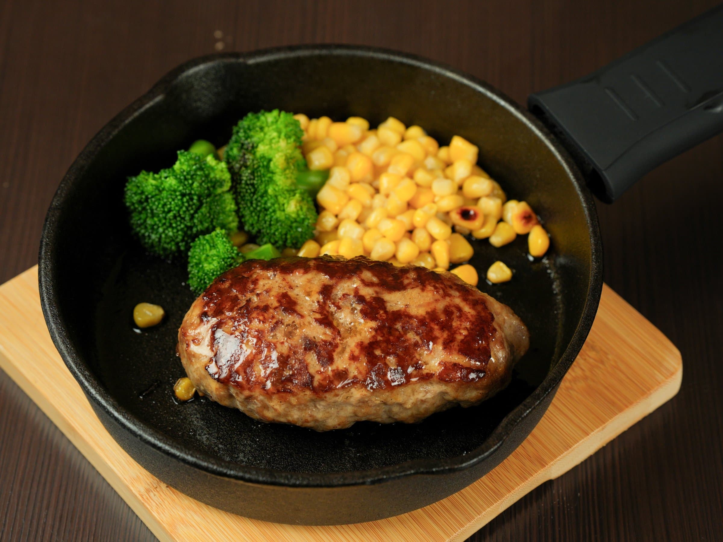 Hakuba Marukin dinner spread of grilled hamburger steak, fried chicken, miso hotpot and local set-meal dishes on a dark table