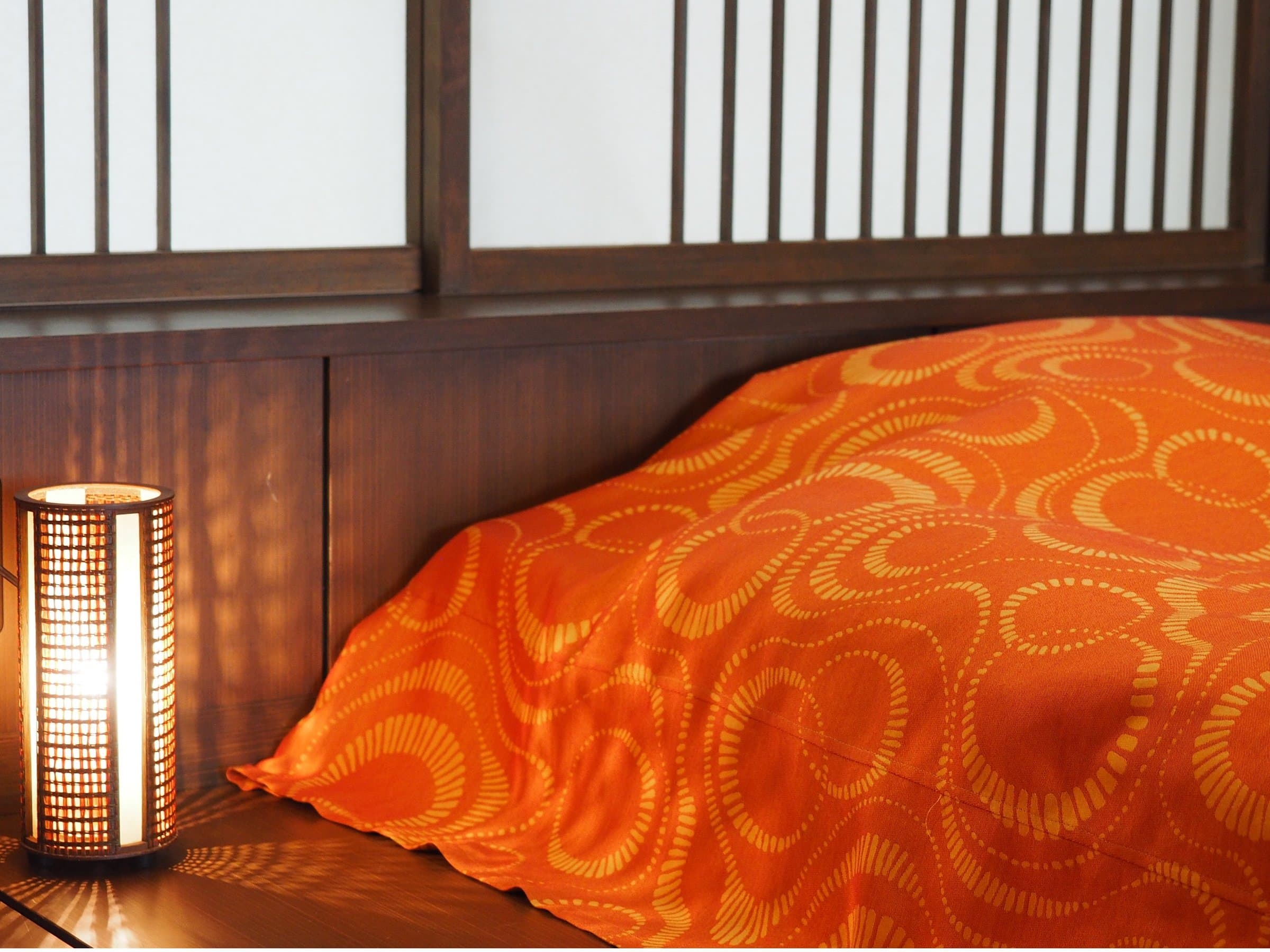 Single futon laid out beside a glowing lantern in a tatami room at Hakuba Marukin Ryokan, an intimate evening detail