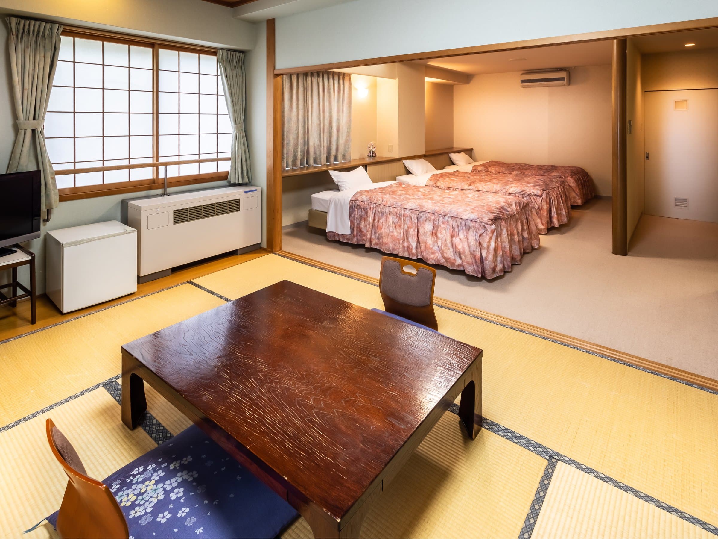 Japanese-style room with bed area at Hakuba Marukin Ryokan, combining tatami floor seating with twin beds