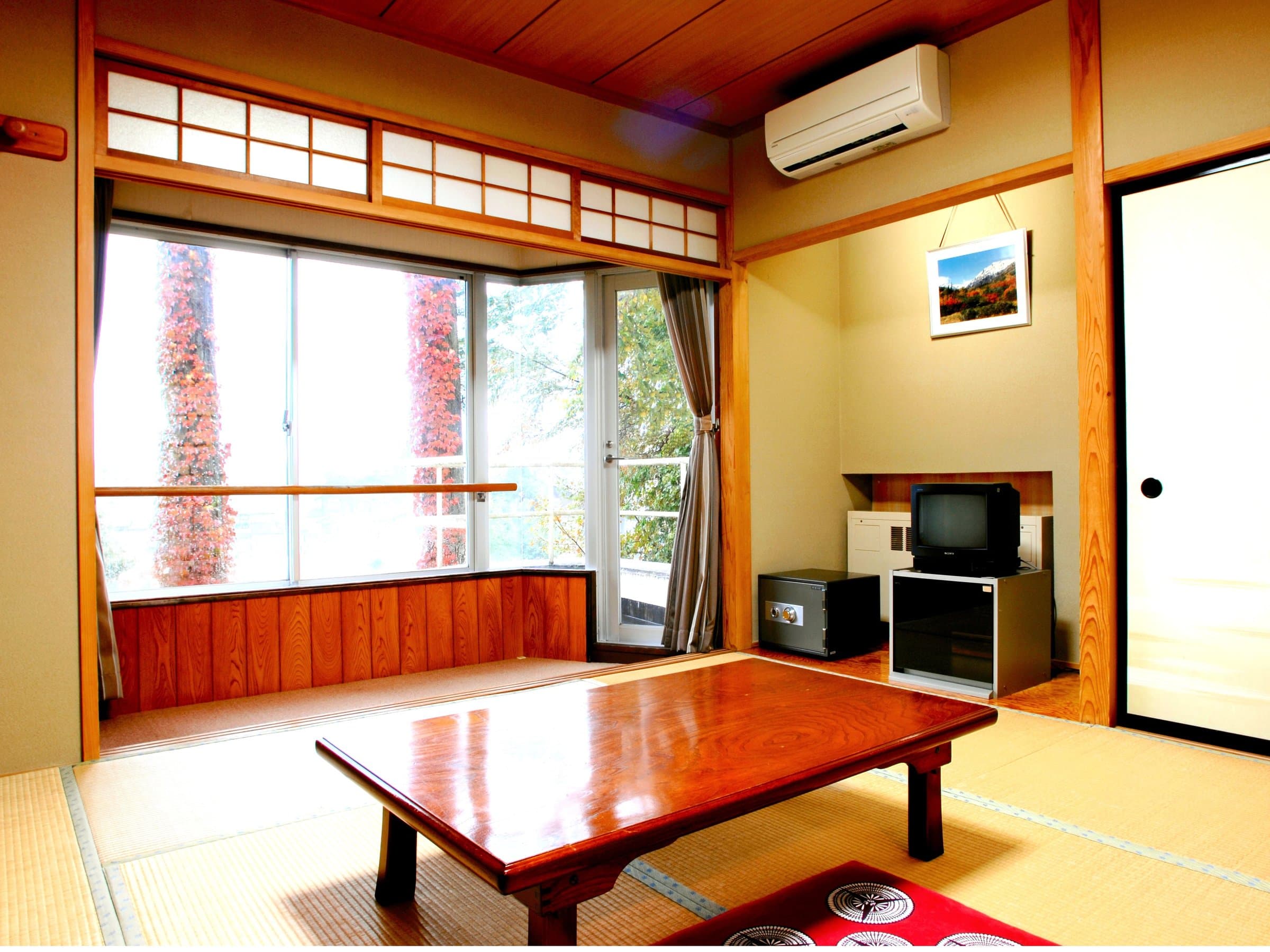 Tatami guest room at Hakuba Marukin Ryokan with low table and a bay window framing the surrounding greenery