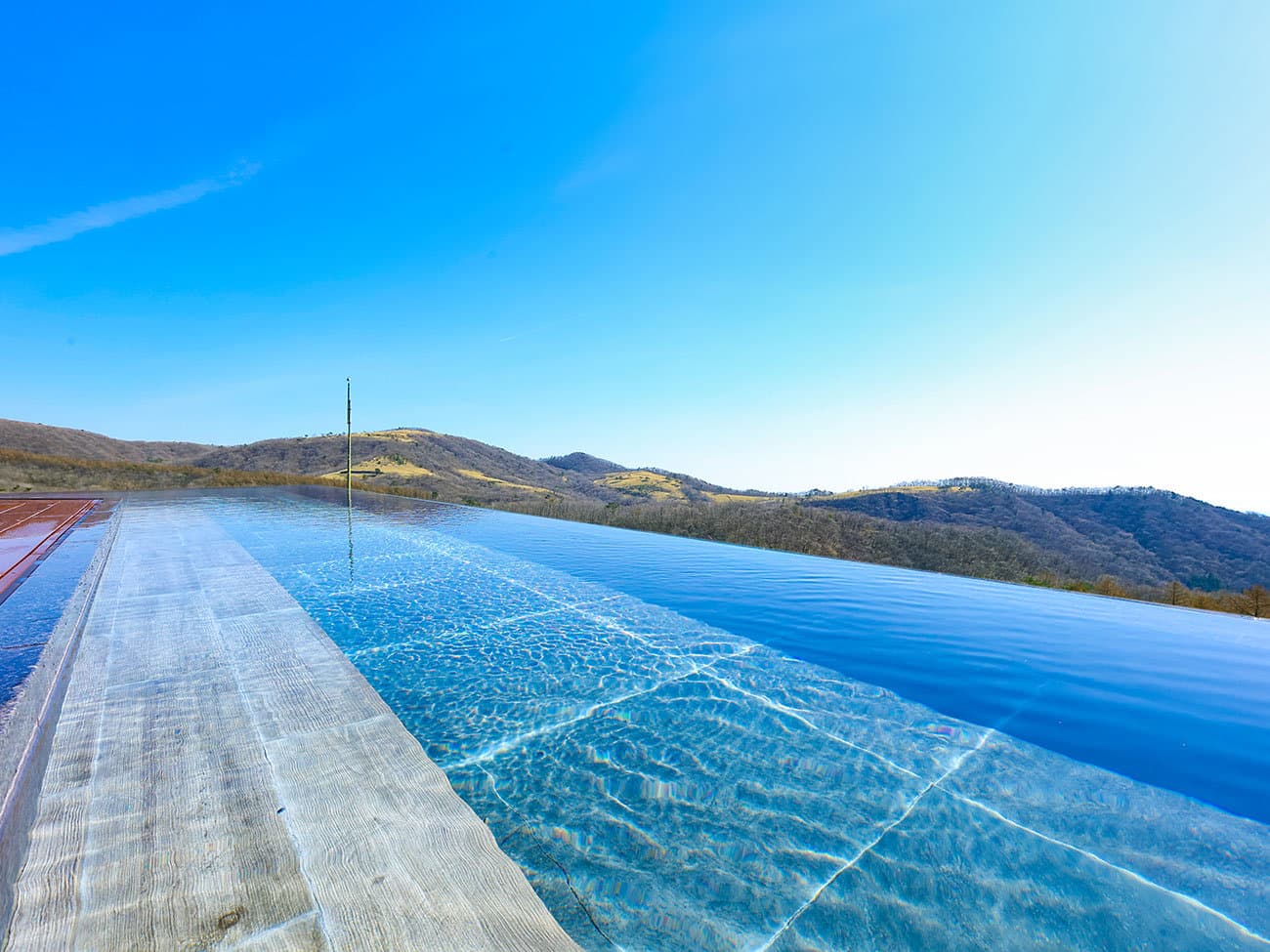 Open-air infinity onsen at TAOYA Nikko Kirifuri under clear sky with a sweeping Nikko mountain view
