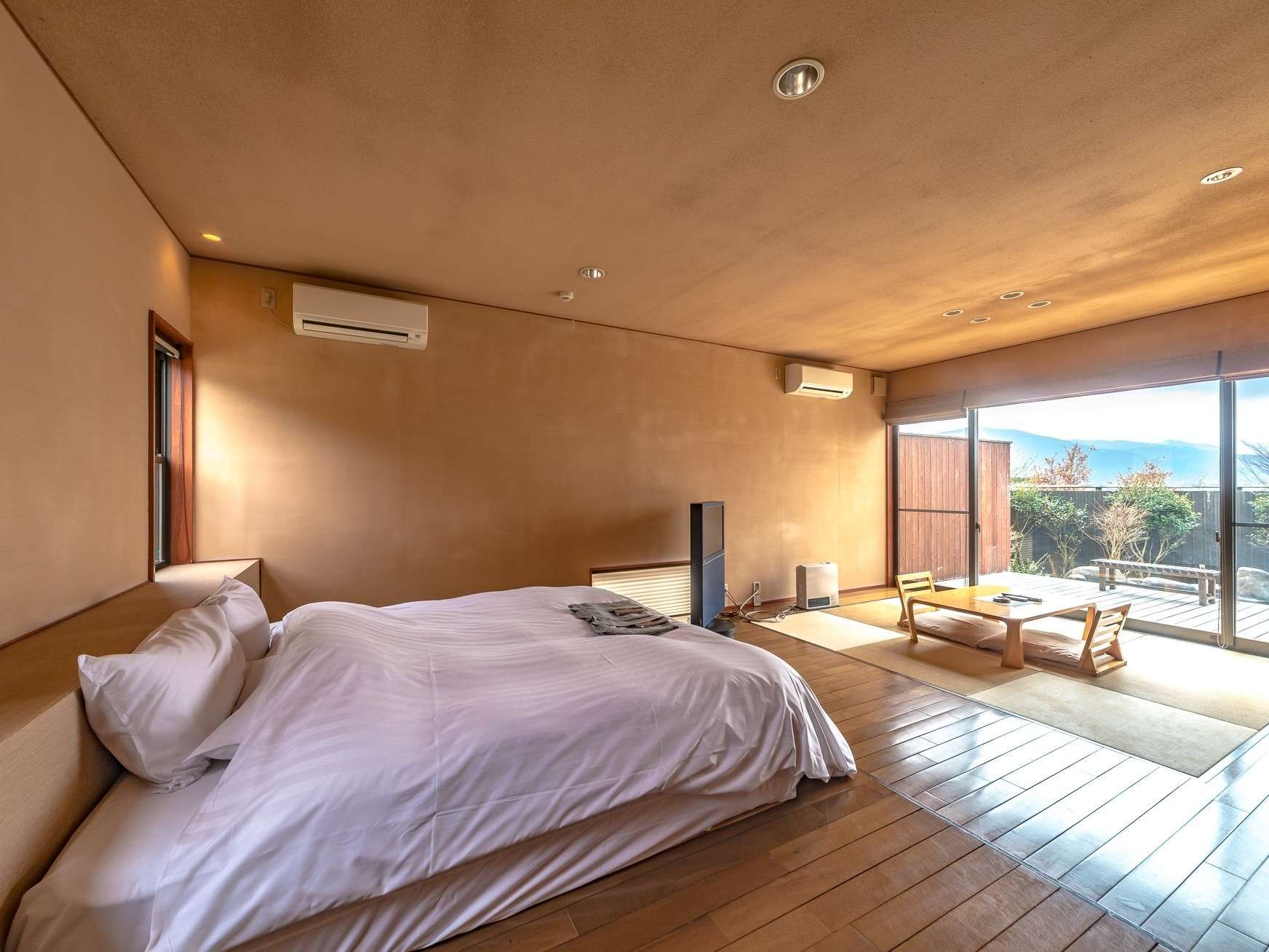 Spacious guest room with low bed, tatami corner and private terrace overlooking the Yufuin mountains