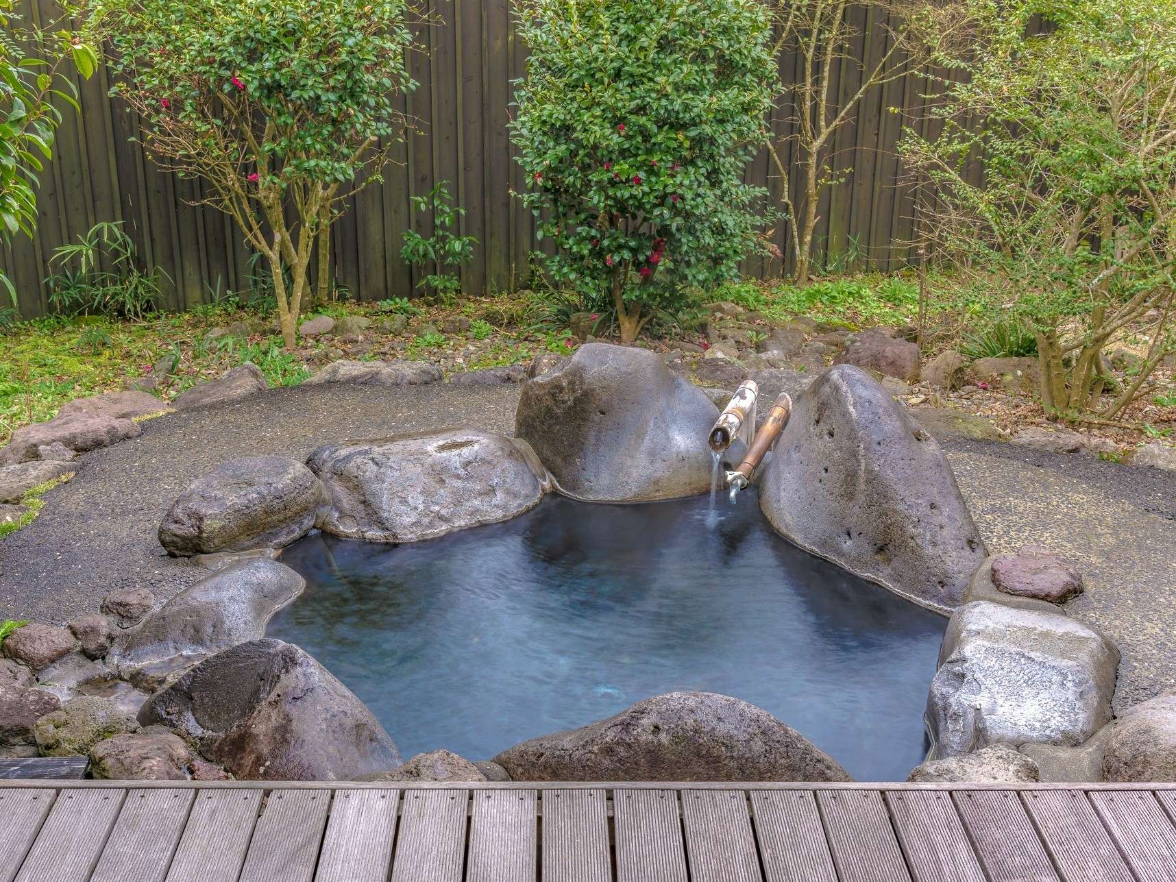 Private rock-rimmed open-air rotenburo onsen bath in a quiet garden at Yuhri, Yufuin
