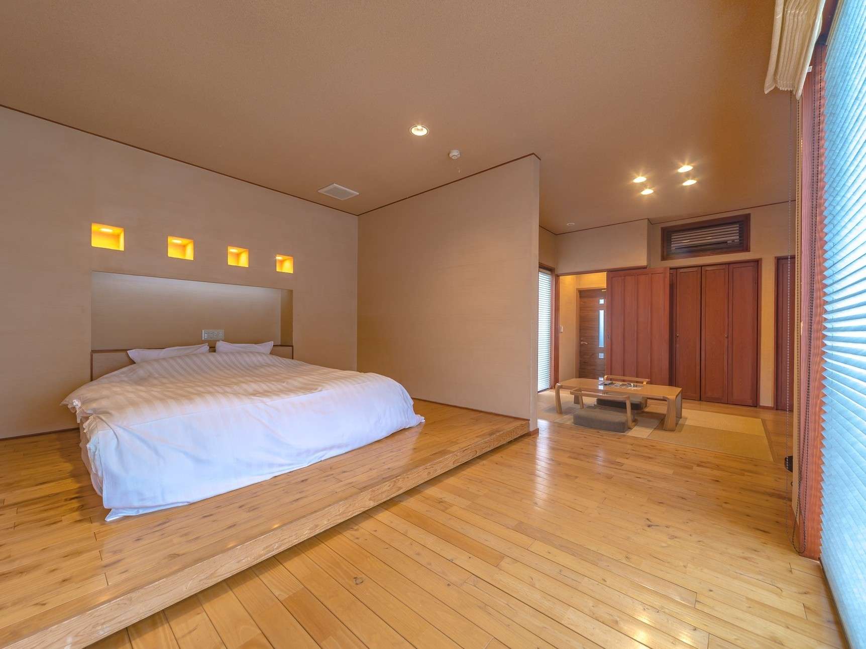 Premium guest room at Yuhri with wide bed, indirect accent lighting and wooden floors