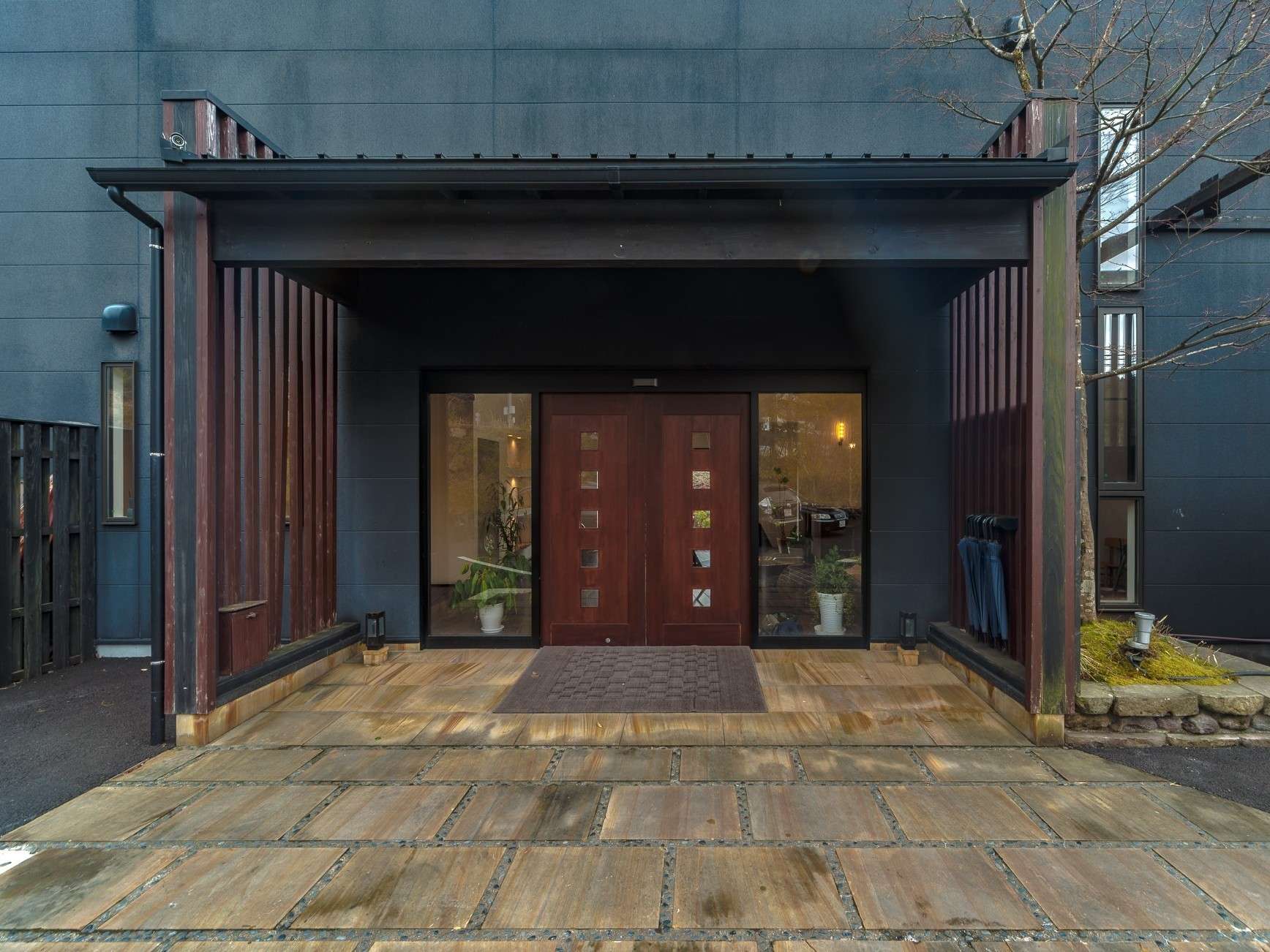 Dark timber entrance facade and stone-paved approach of Yuhri ryokan in Yufuin