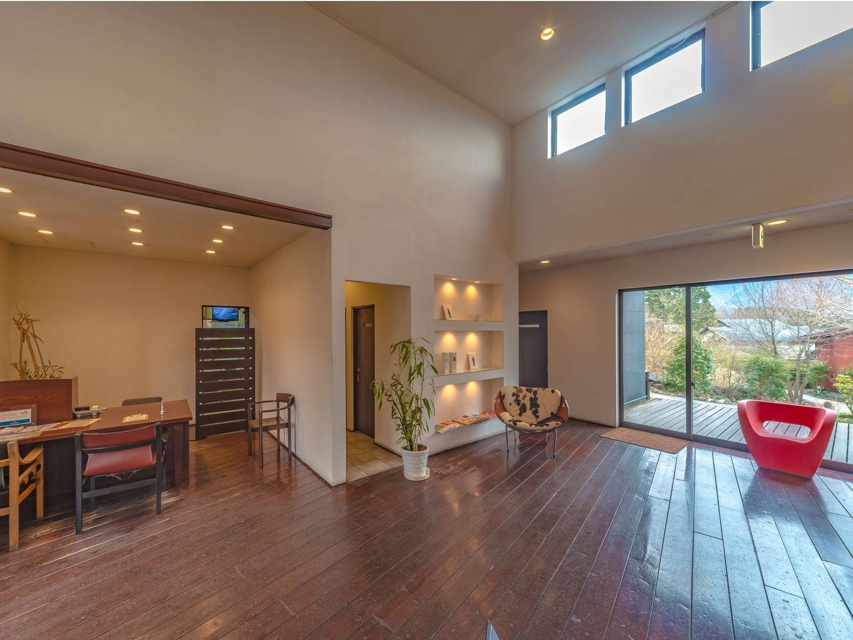 High-ceilinged lobby lounge with reception desk and large garden-view windows
