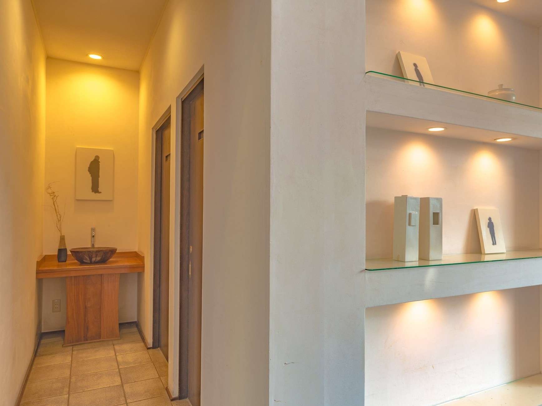 Minimalist interior hallway with carved wooden washbasin and lit display niches