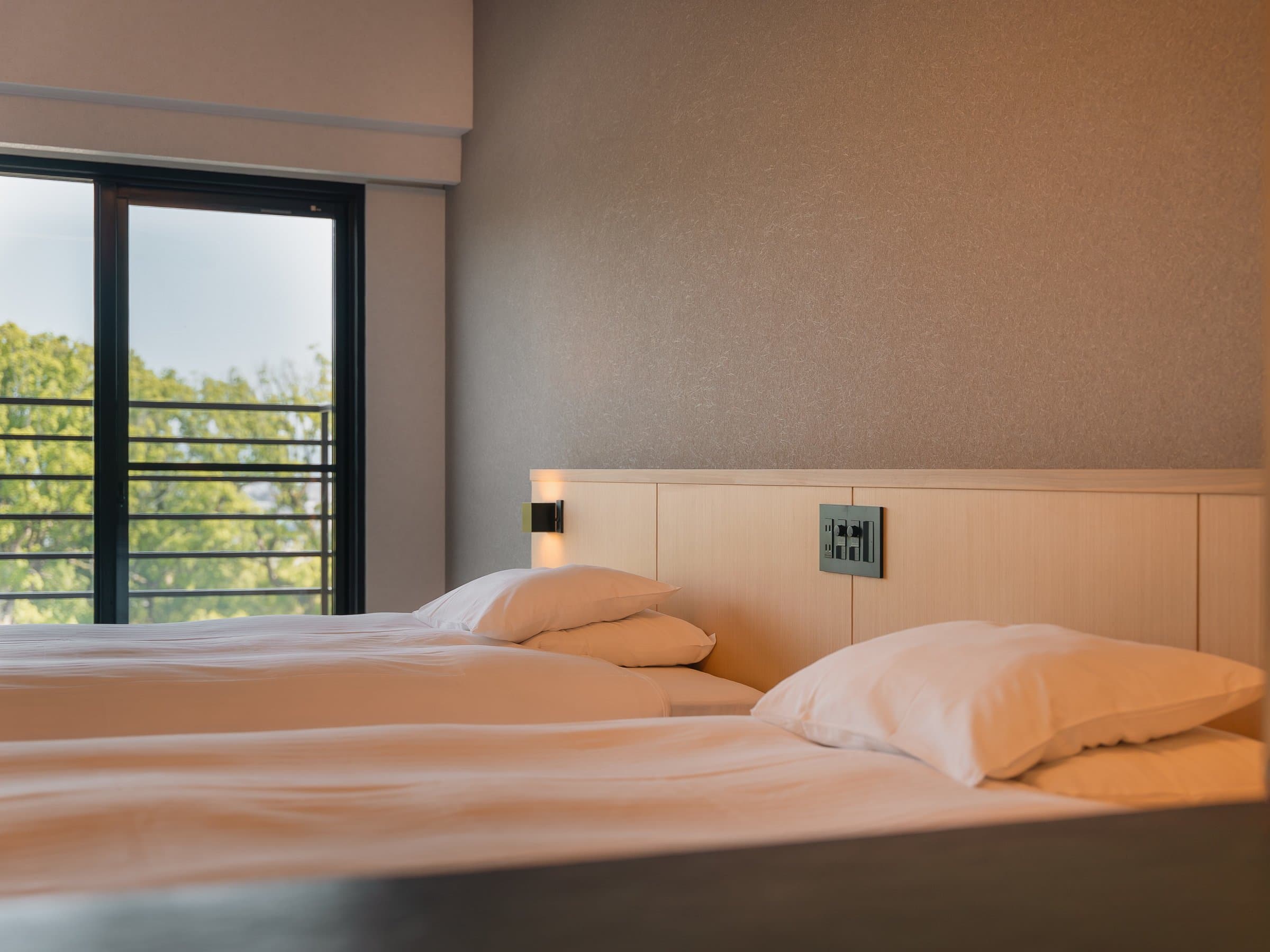Warmly lit twin beds with shoji-style lattice headboard panel at Hotel Higuchiken