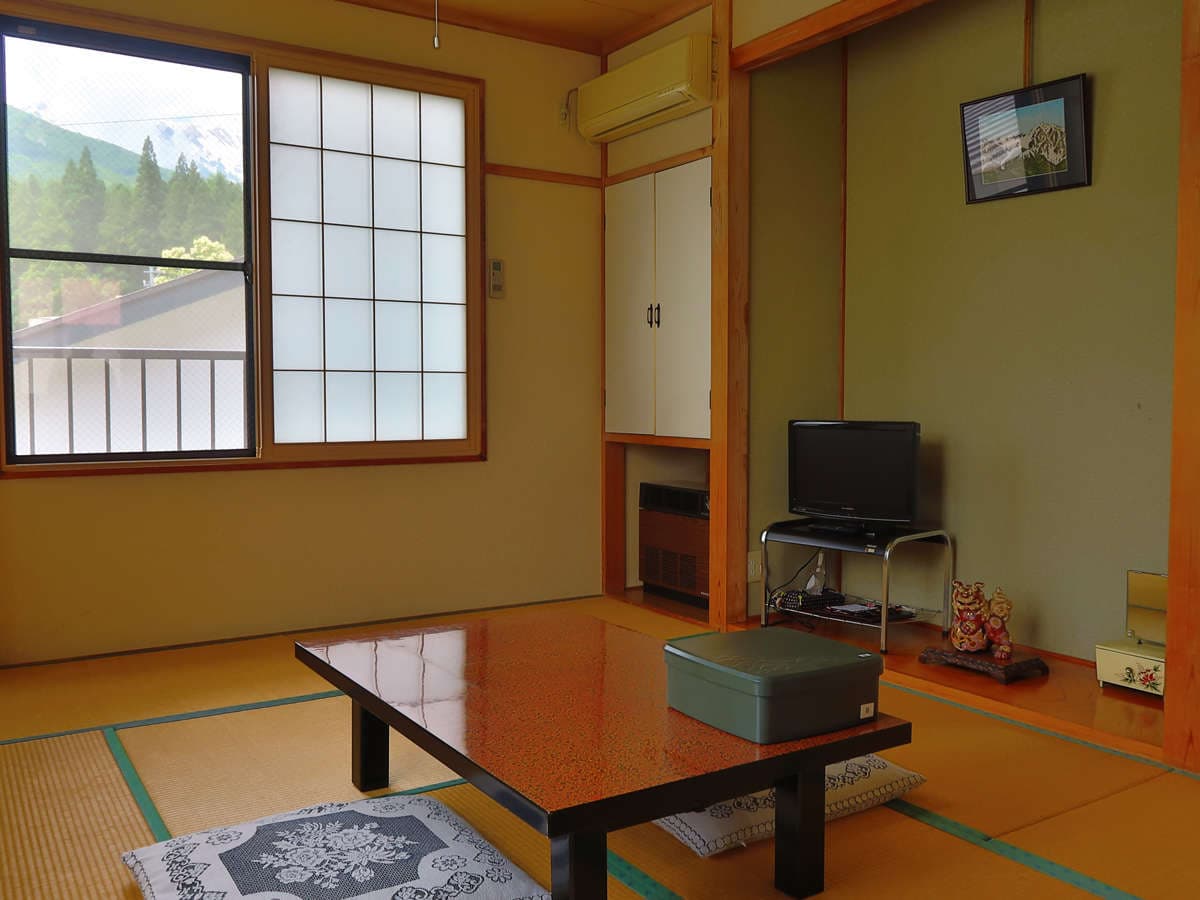 Traditional tatami guest room at Ryokan Furuya with low table and Hakuba mountain view through the window