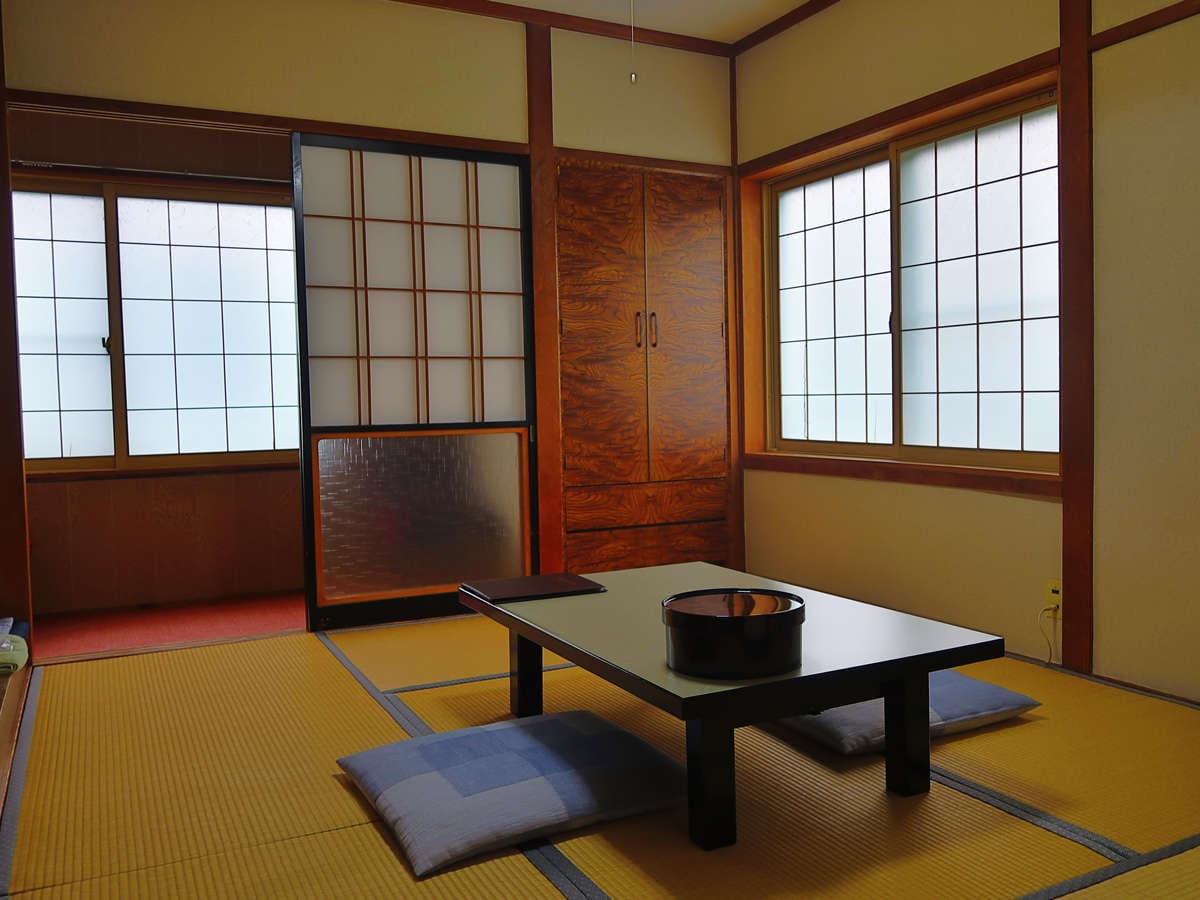 Bright tatami guest room at Ryokan Furuya with shoji windows, wooden cabinet and floor cushions