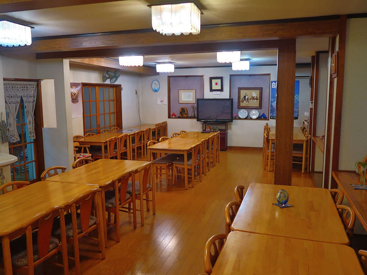 Dining hall at Ryokan Furuya with wooden tables and chairs and Hakuba decorations on the walls