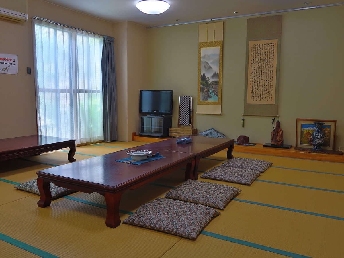 Spacious tatami room at Ryokan Furuya with hanging scrolls, low lacquer table and floor cushions