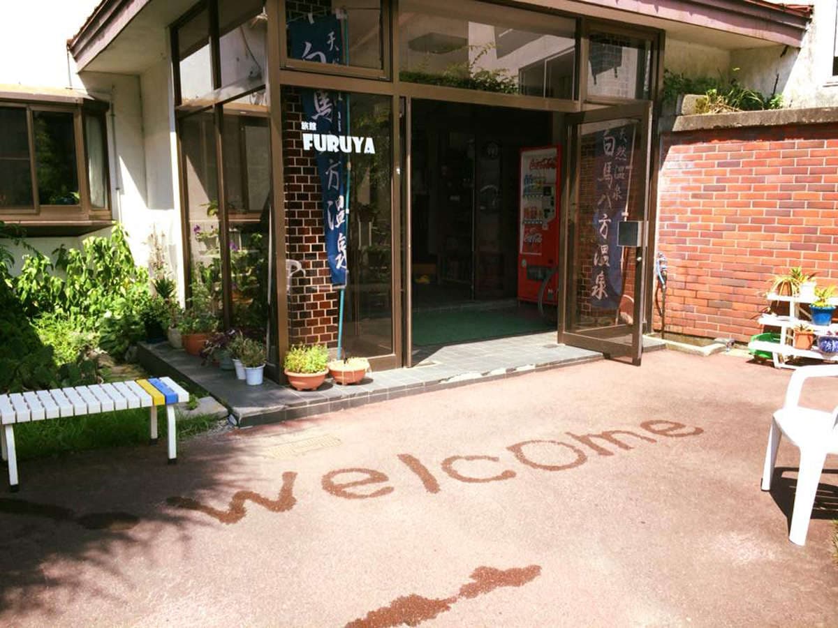 Entrance of Ryokan Furuya in Hakuba Happo Onsen with brick facade, Furuya signage and a welcome path