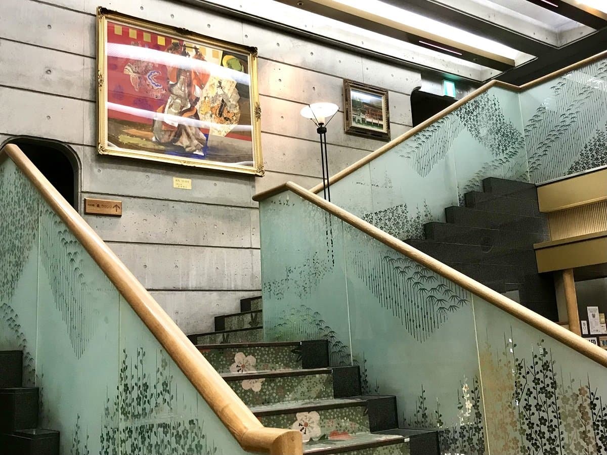Interior staircase with frosted glass crane motif railing and Japanese art at Miyajima Hotel Makoto