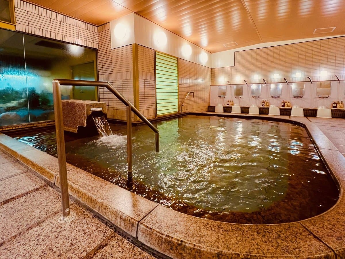 Rounded indoor hot spring bath with bubbling water and warm lighting at Miyajima Hotel Makoto