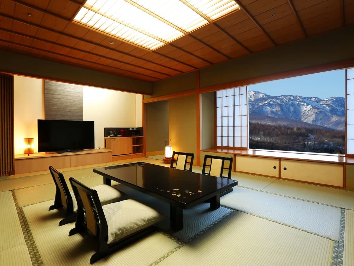 Tatami guest room at Hotel Sakurai with floor seating and a picture window overlooking snow-capped mountains