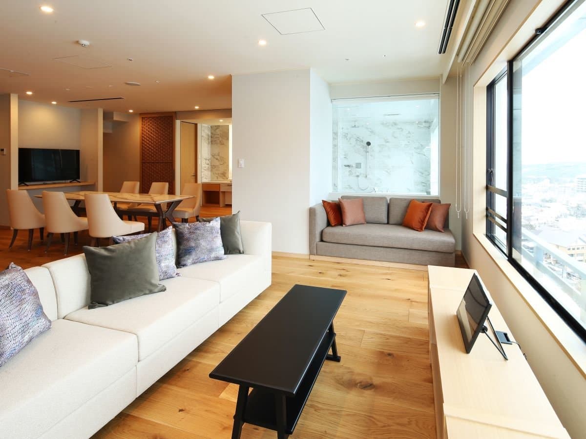 Premium suite living room at Hotel Sakurai with sofas, dining area and a town view through floor-to-ceiling windows