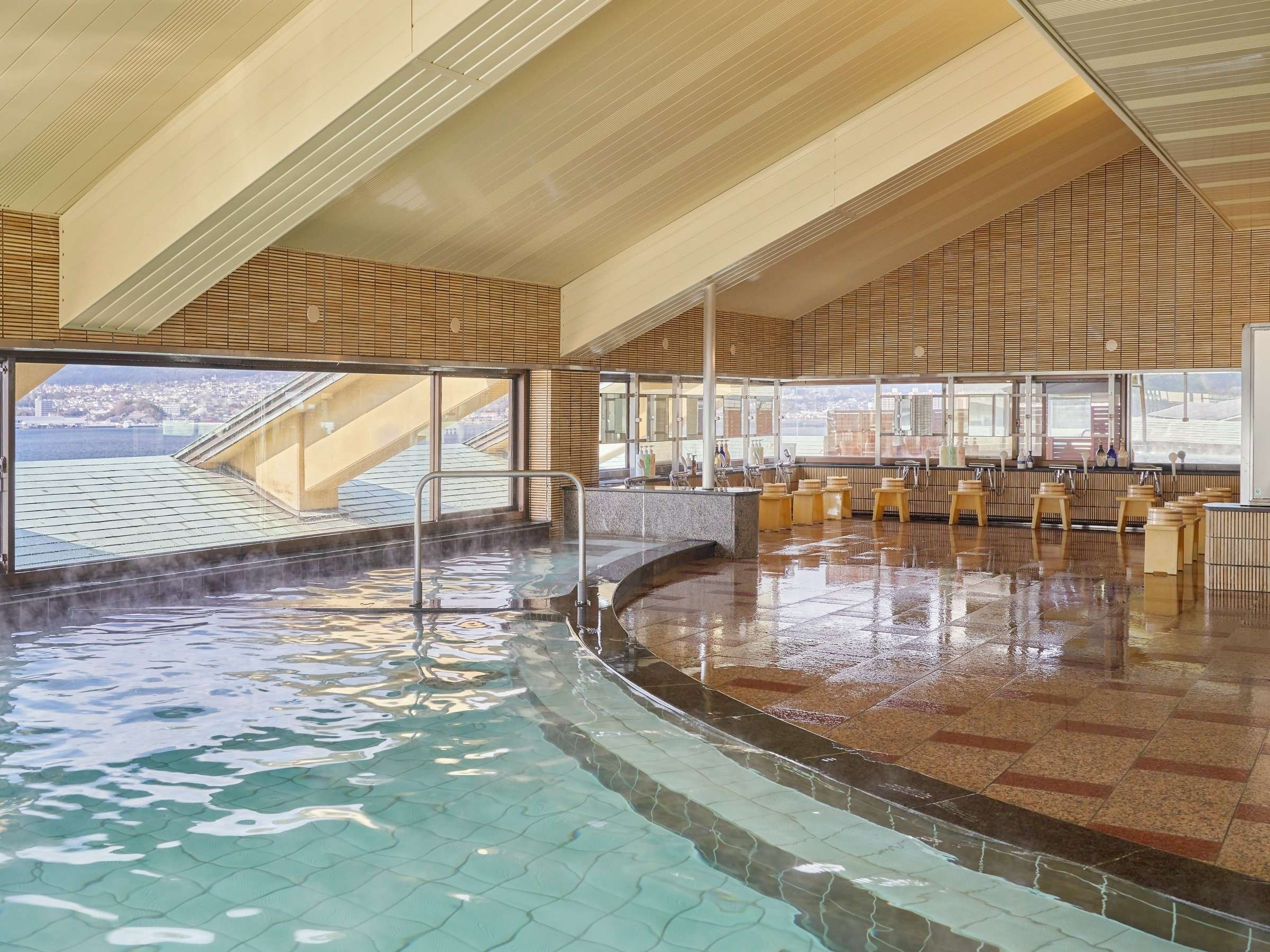 Curved indoor hot spring bath under a vaulted wooden ceiling with panoramic sea views at Hotel Miyarikyu