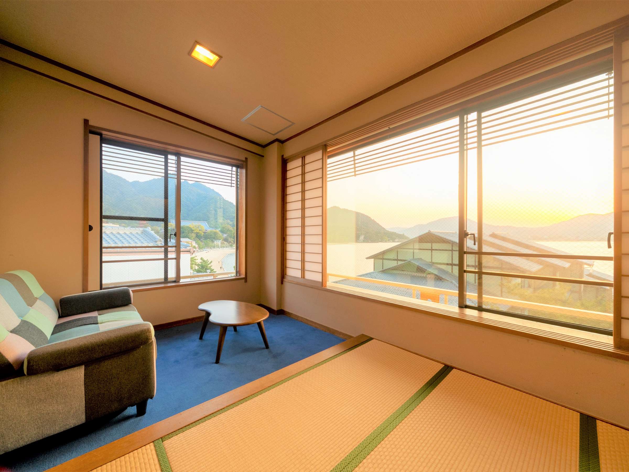 Sea-facing Japanese tatami guest room at Hotel Miyarikyu with shoji screens and golden sunset light over the bay