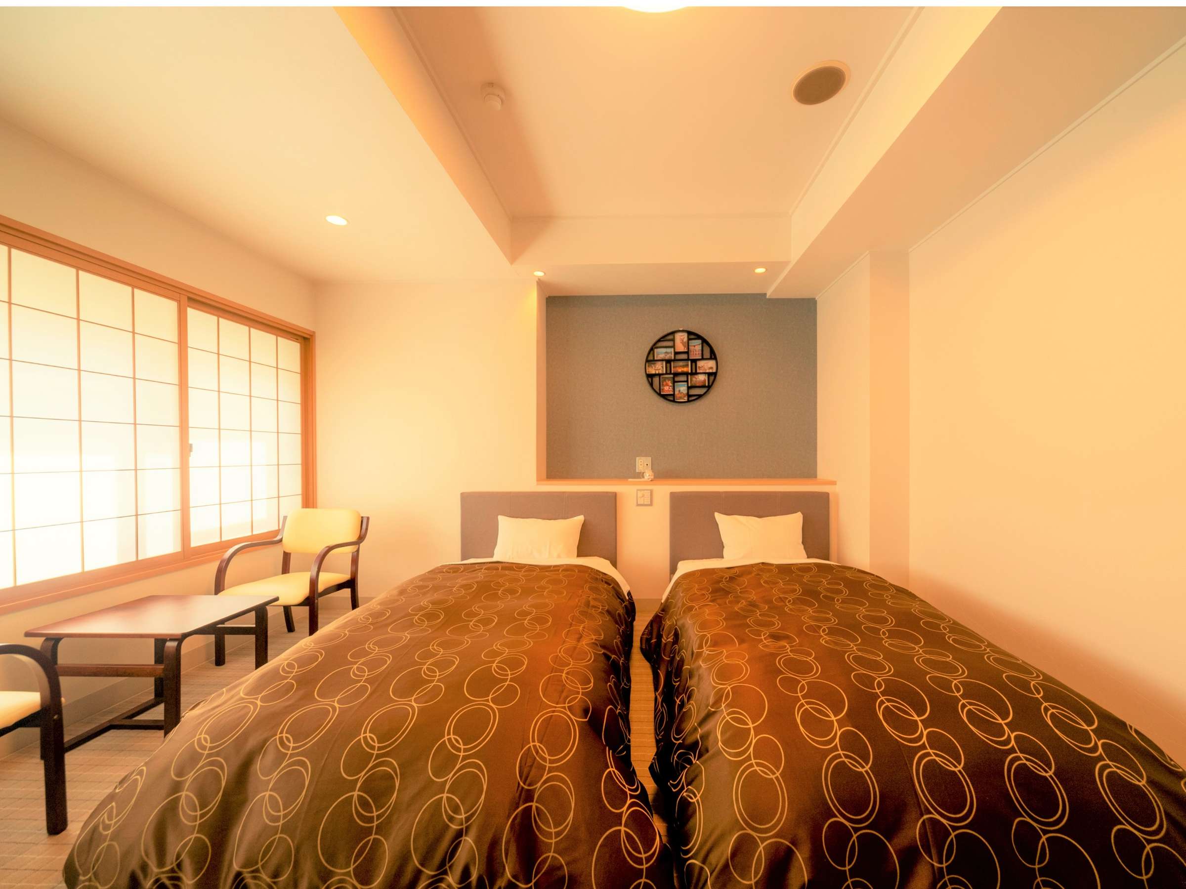 Twin-bed Western-style guest room at Hotel Miyarikyu with shoji windows and a round decorative wall shelf