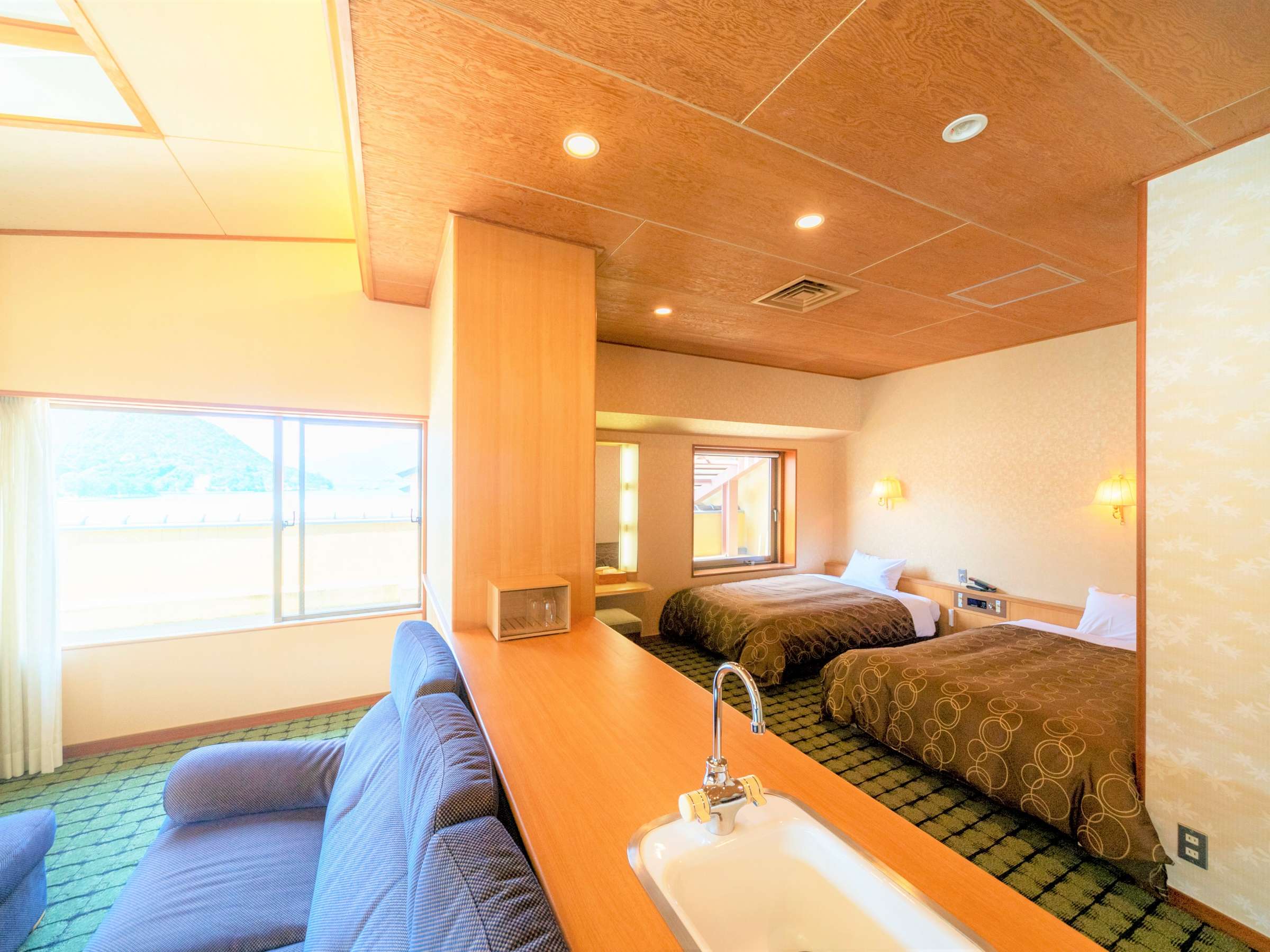 Maisonette-style twin guest room at Hotel Miyarikyu with a sofa lounge area and sea-view windows